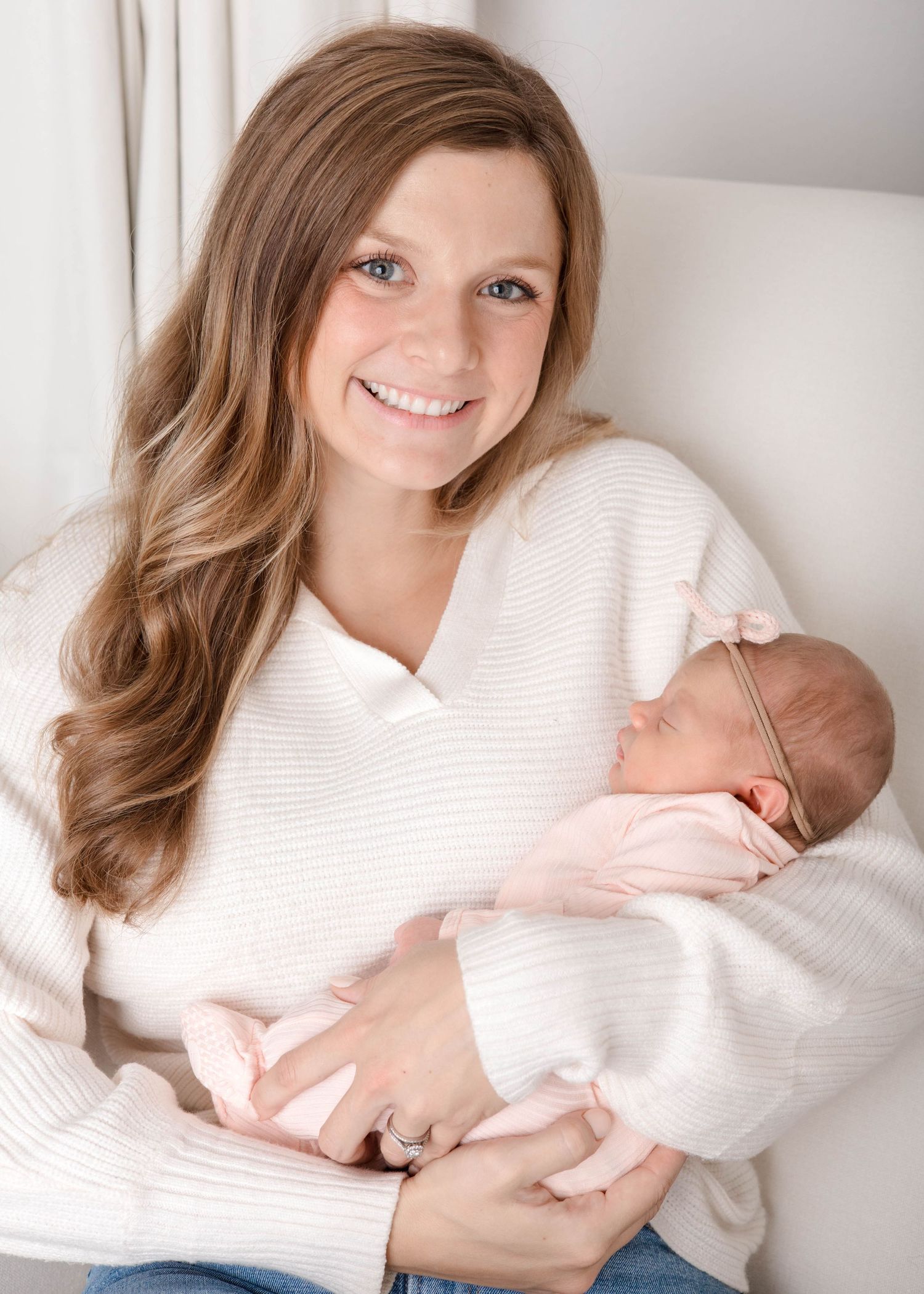 A person in a white sweater holds and gazes lovingly at a sleeping newborn baby in a series of tender portraits.