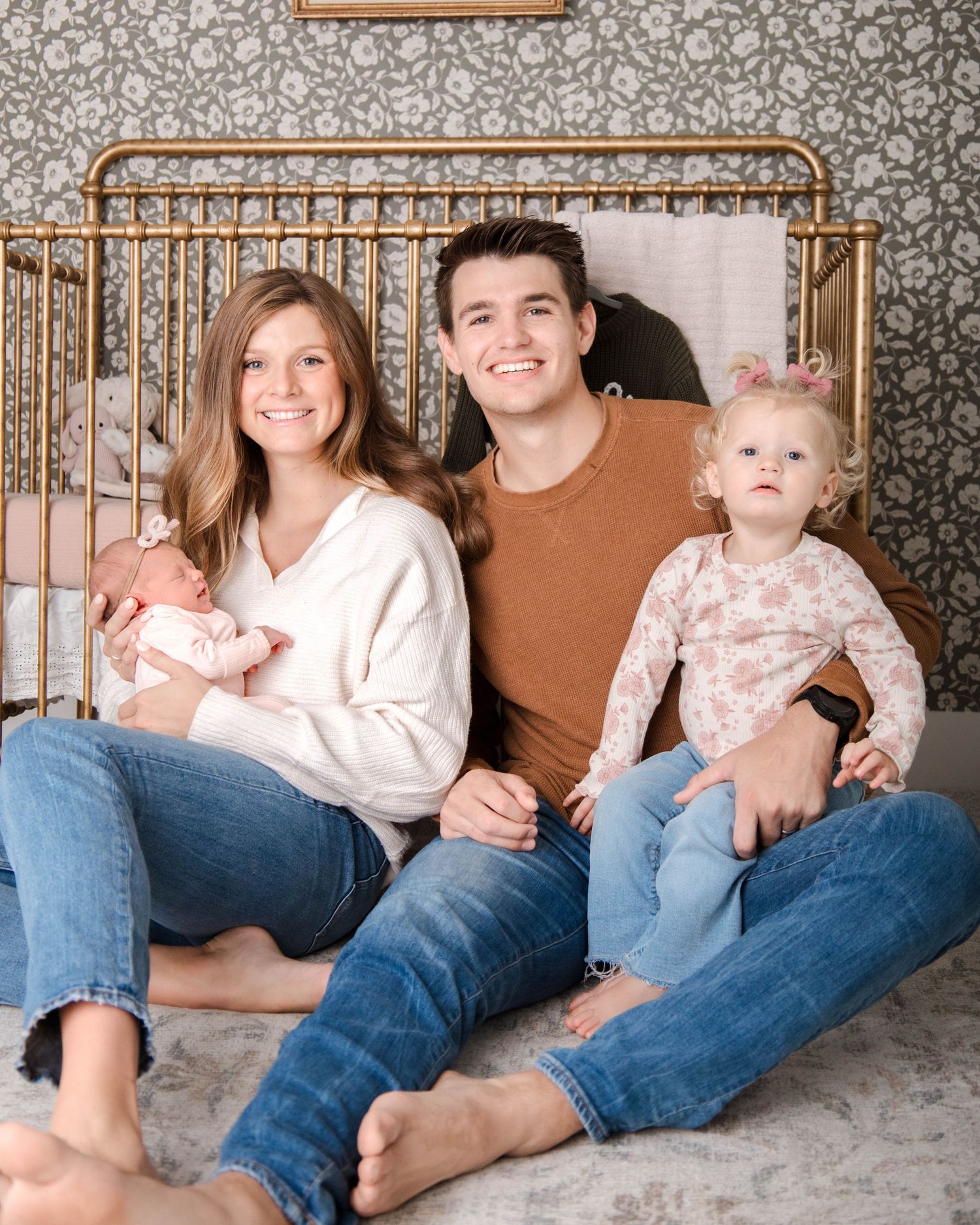 Family members sitting together on a cozy gray carpet, wearing casual jeans and neutral colored tops.