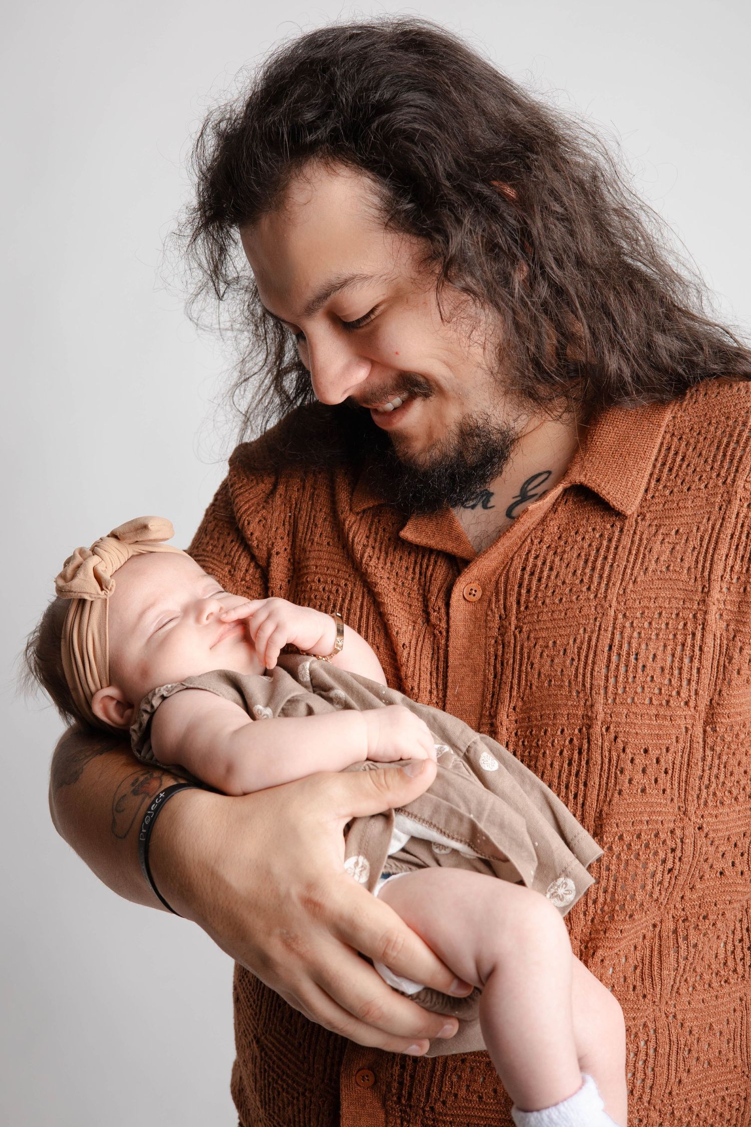 Parent in brown sweater sharing sweet moments with baby in natural studio lighting.