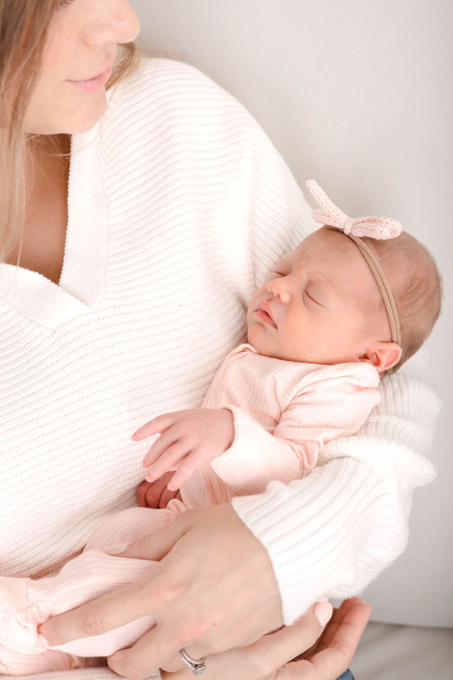 Tender moment of a sleeping baby in soft pink clothing resting peacefully on white bedding.