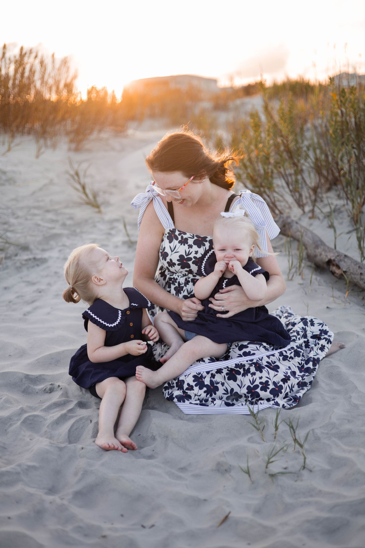 Candid family moment captured on sandy beach with warm sunset lighting.