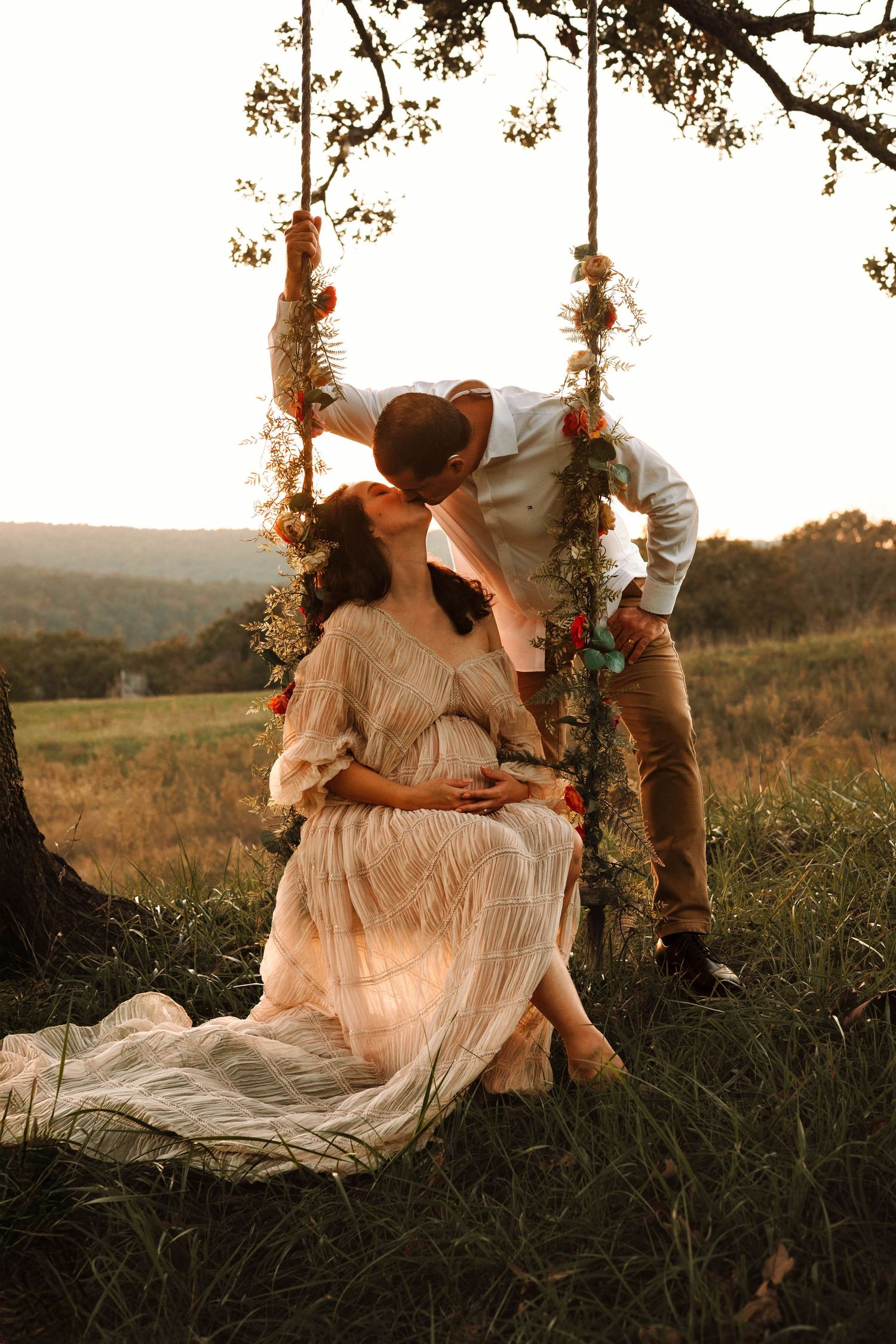 A dreamy scene of a person in a flowing white dress sitting on a tree swing at golden hour in a meadow.