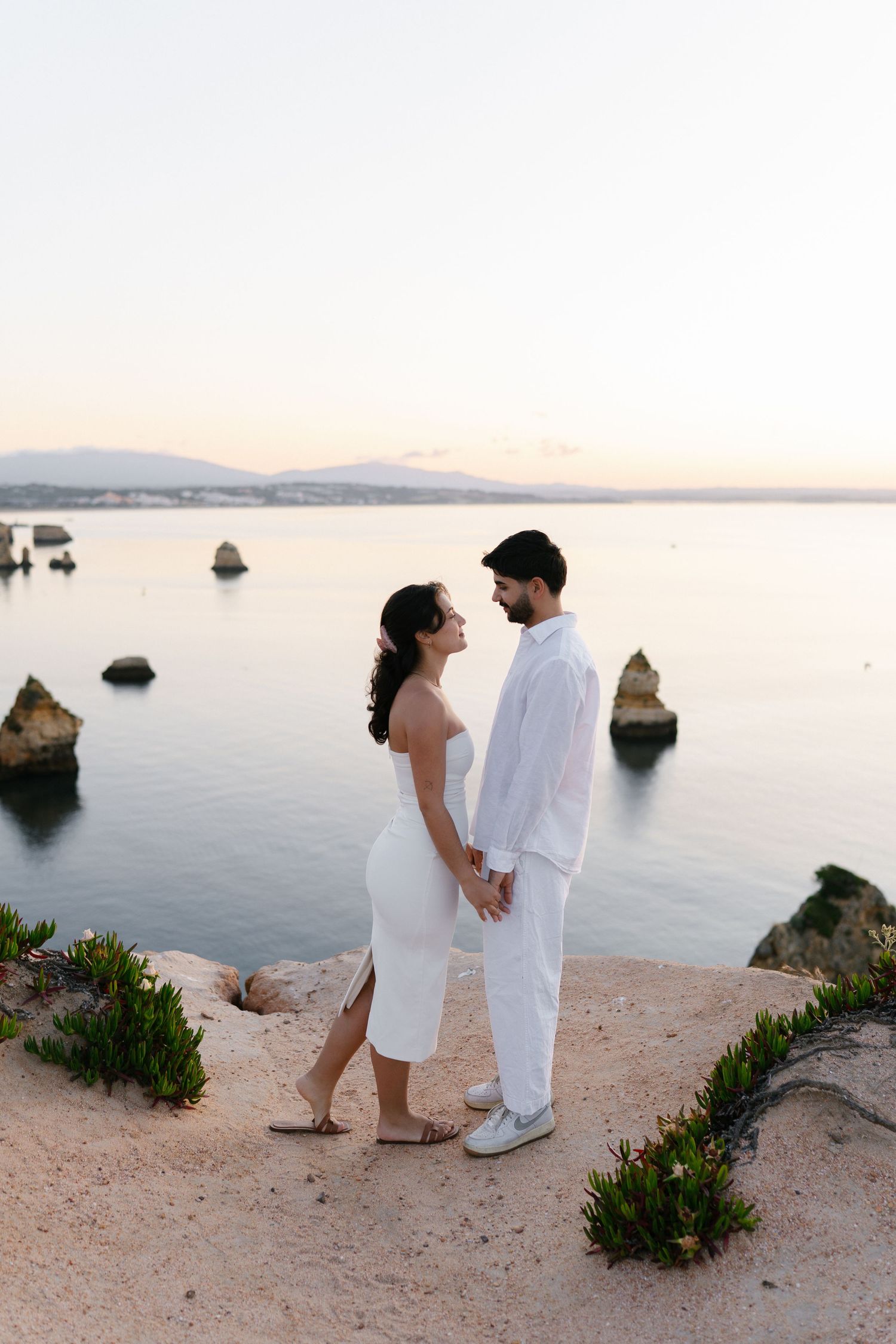 Romantic couple sharing a beautiful moment at sunrise with the scenic cliffs of Lagos in the background