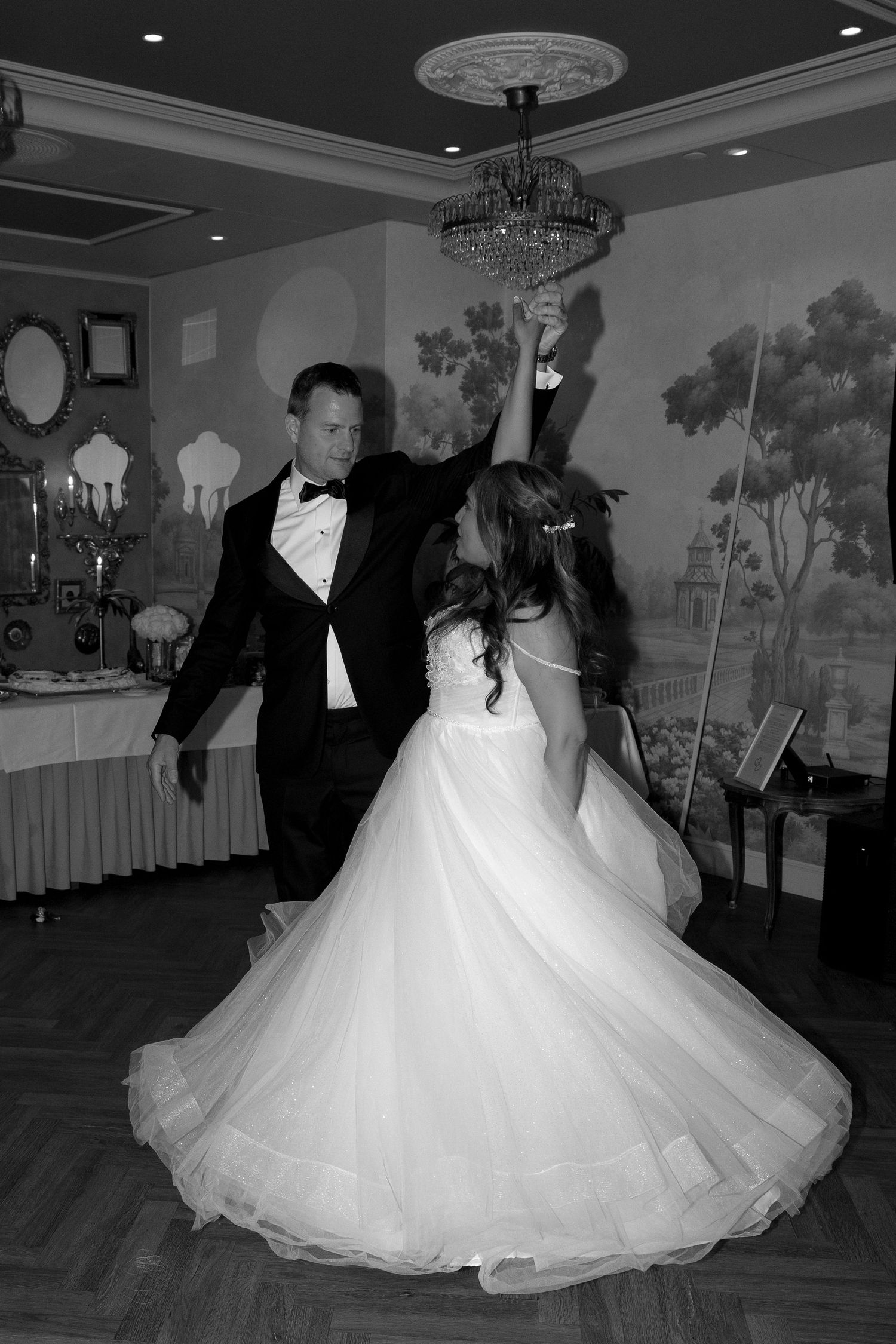 Black and white photo of bride and groom sharing their first dance at elegant wedding reception.