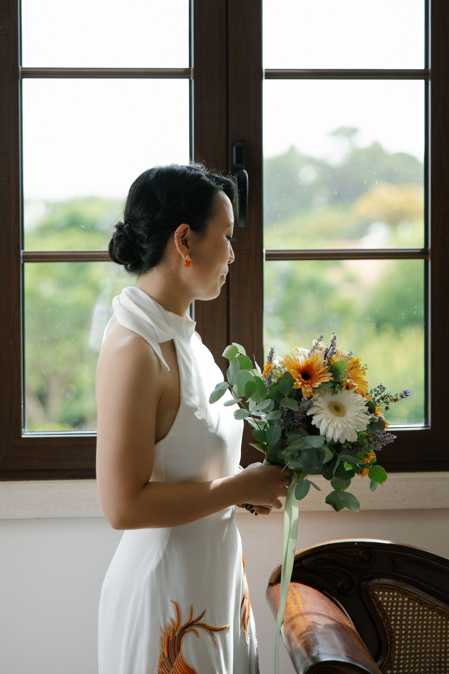 Bride in a white creative wedding dress gazing out of the window before the ceremony