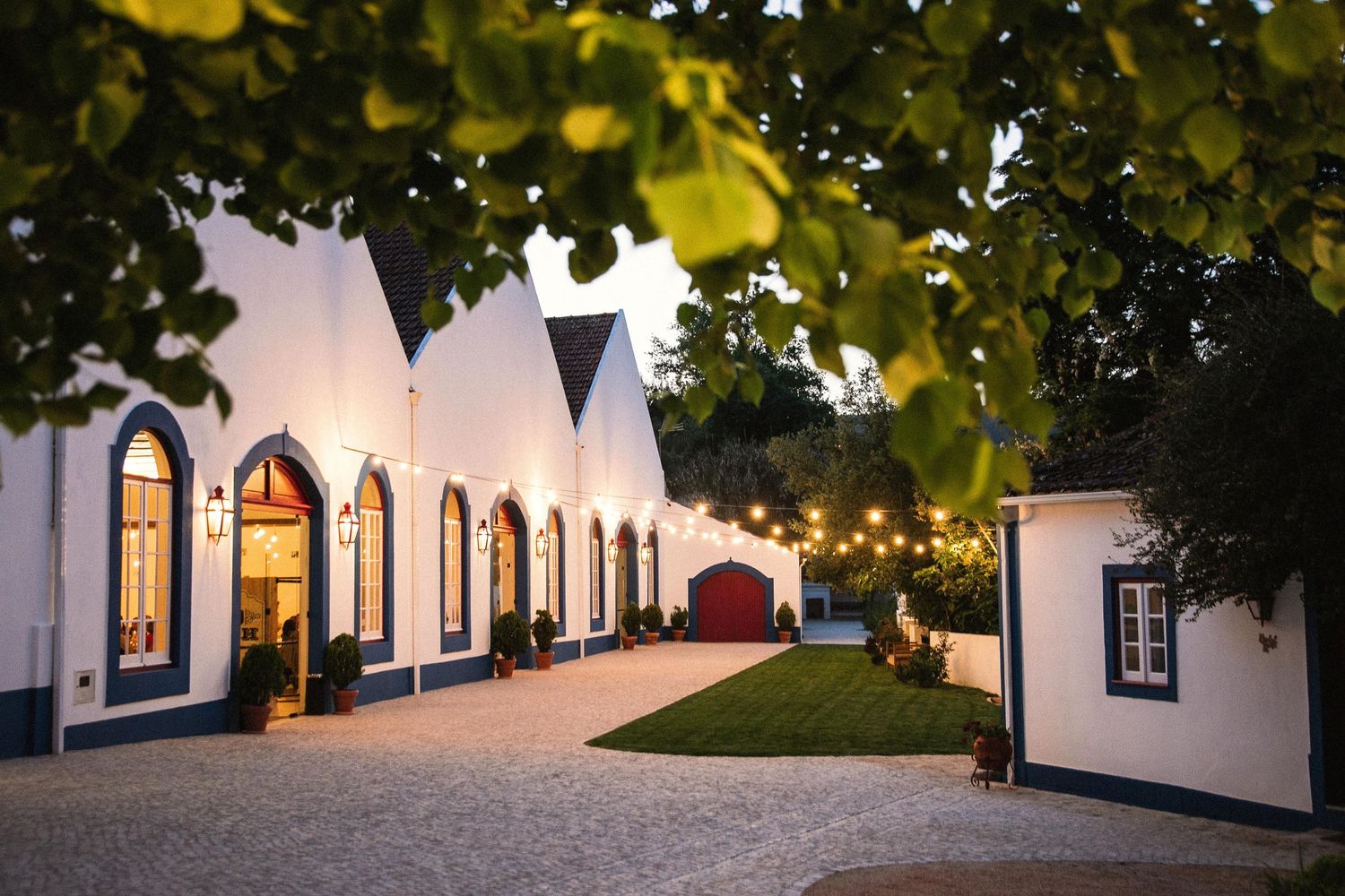 Elegant white wedding venue exterior with arched windows and warm lighting at dusk.