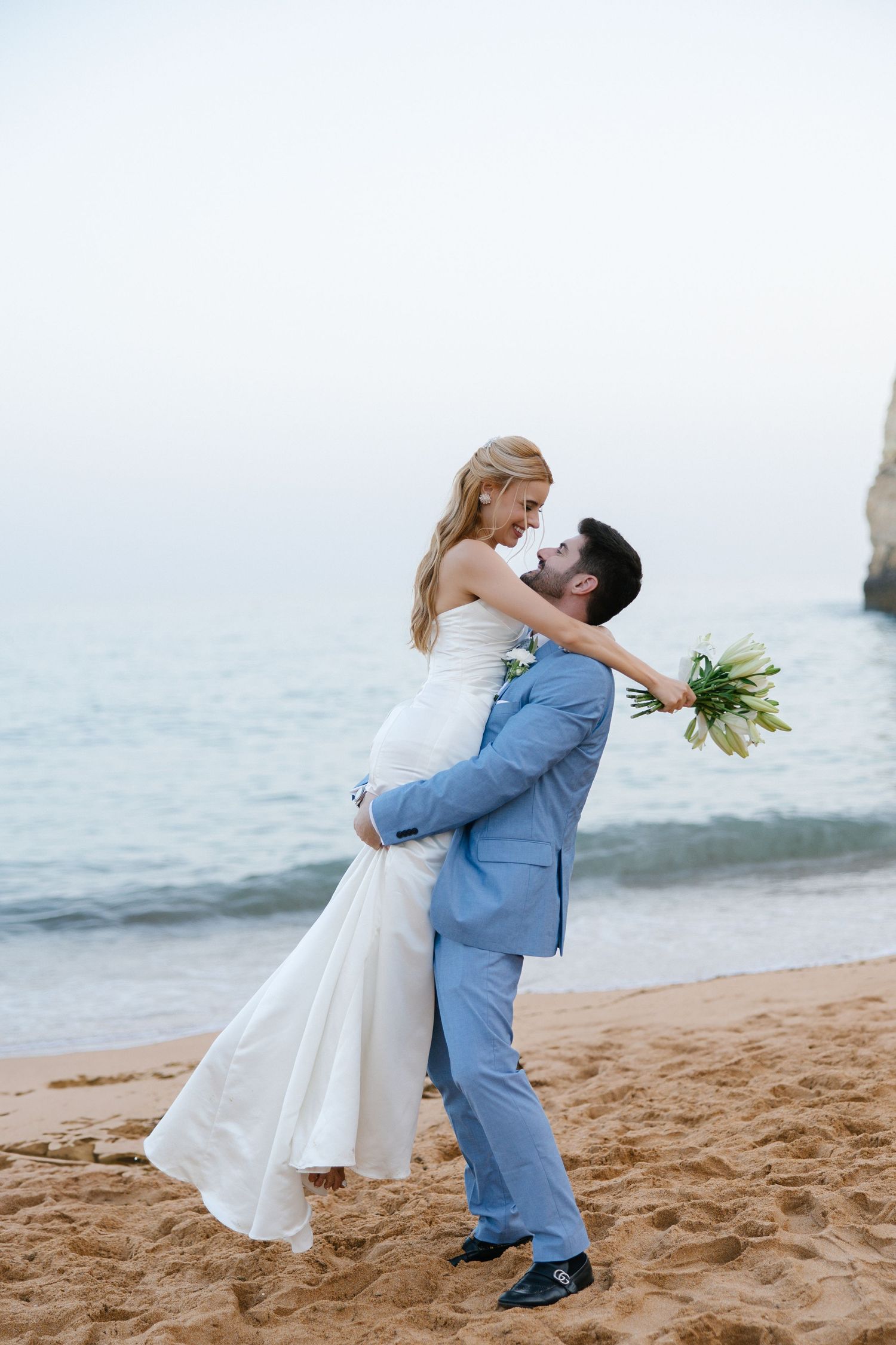 Groom lifting up the bride on the beautiful beach of praia da rocha in the algarve