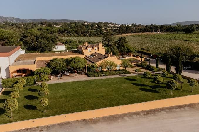 Aerial view of a grand estate wedding venue with manicured gardens, vineyards, and terracotta architecture.