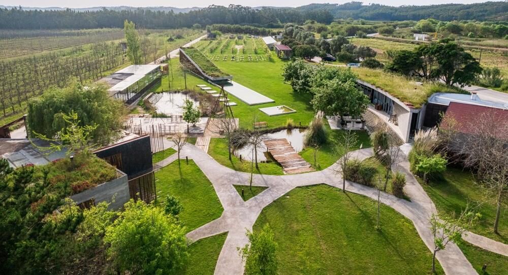 Aerial view of a modern winery estate with manicured gardens, vineyards, and contemporary architectural buildings.