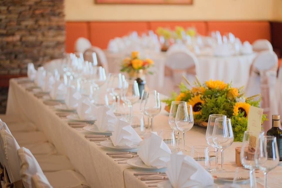 Elegantly set wedding banquet table with white linens, sunflower centerpieces, and crystal glassware.