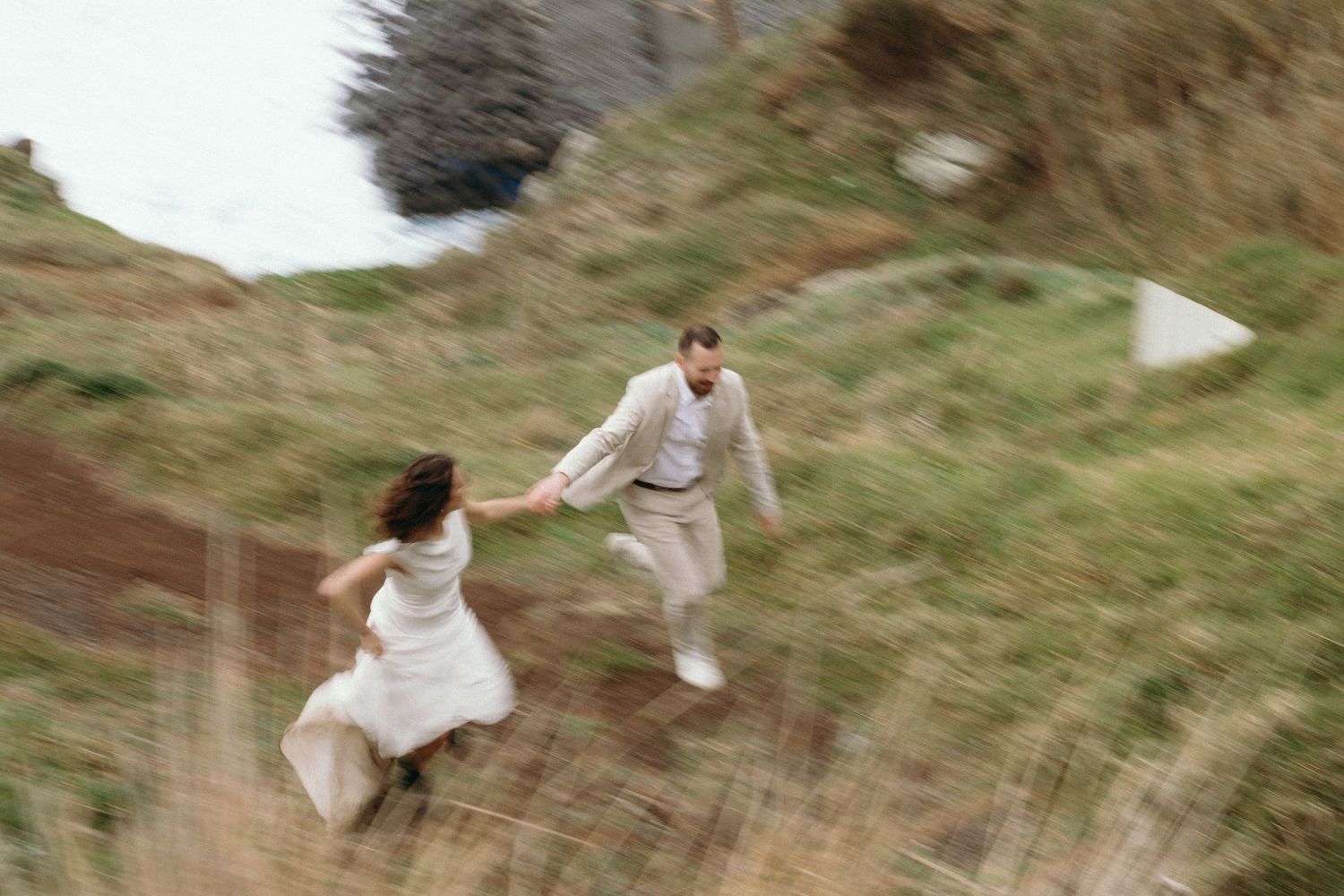 Couple running through golden grass fields in a joyful motion-blurred photo.