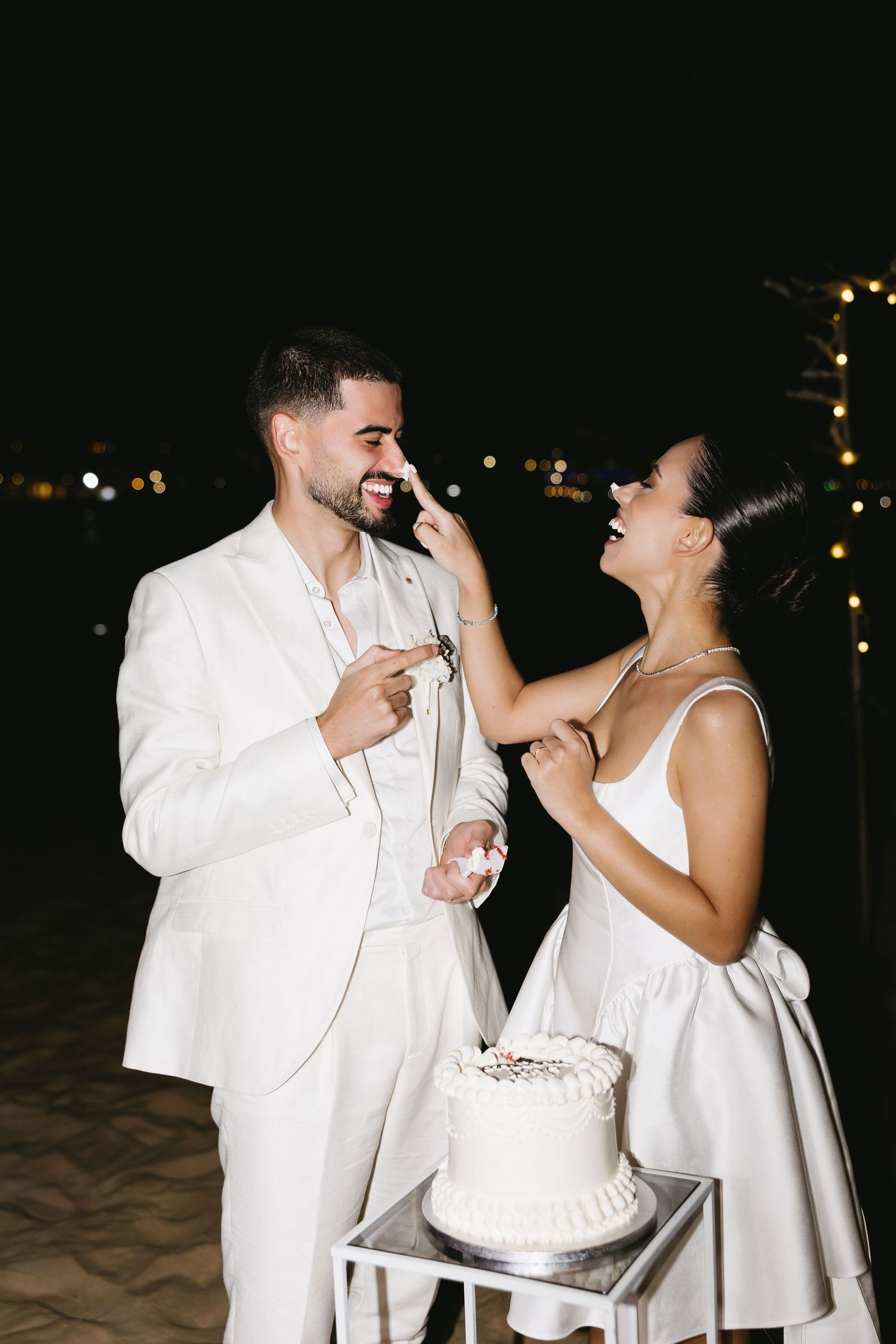 Fun wedding moment of couple smearing cake on each other at celebration