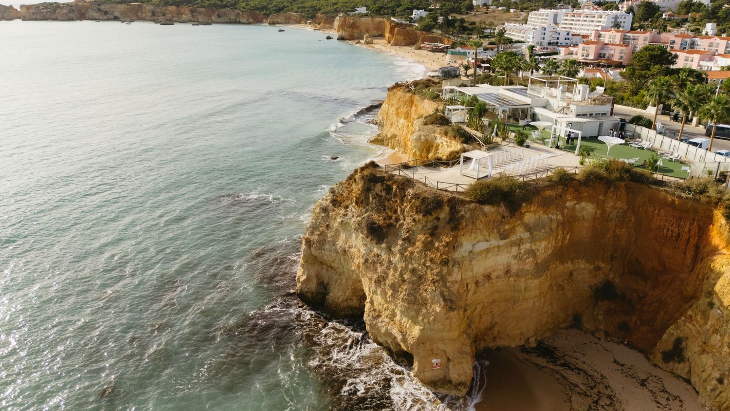 Aerial view of golden cliffs and luxury villas overlooking a serene coastal bay in the Algarve.