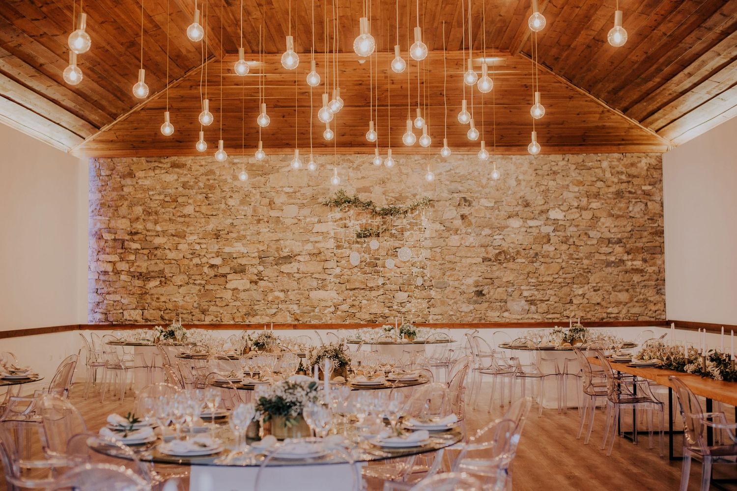 Rustic wedding reception hall with exposed brick walls and hanging Edison bulb lighting.