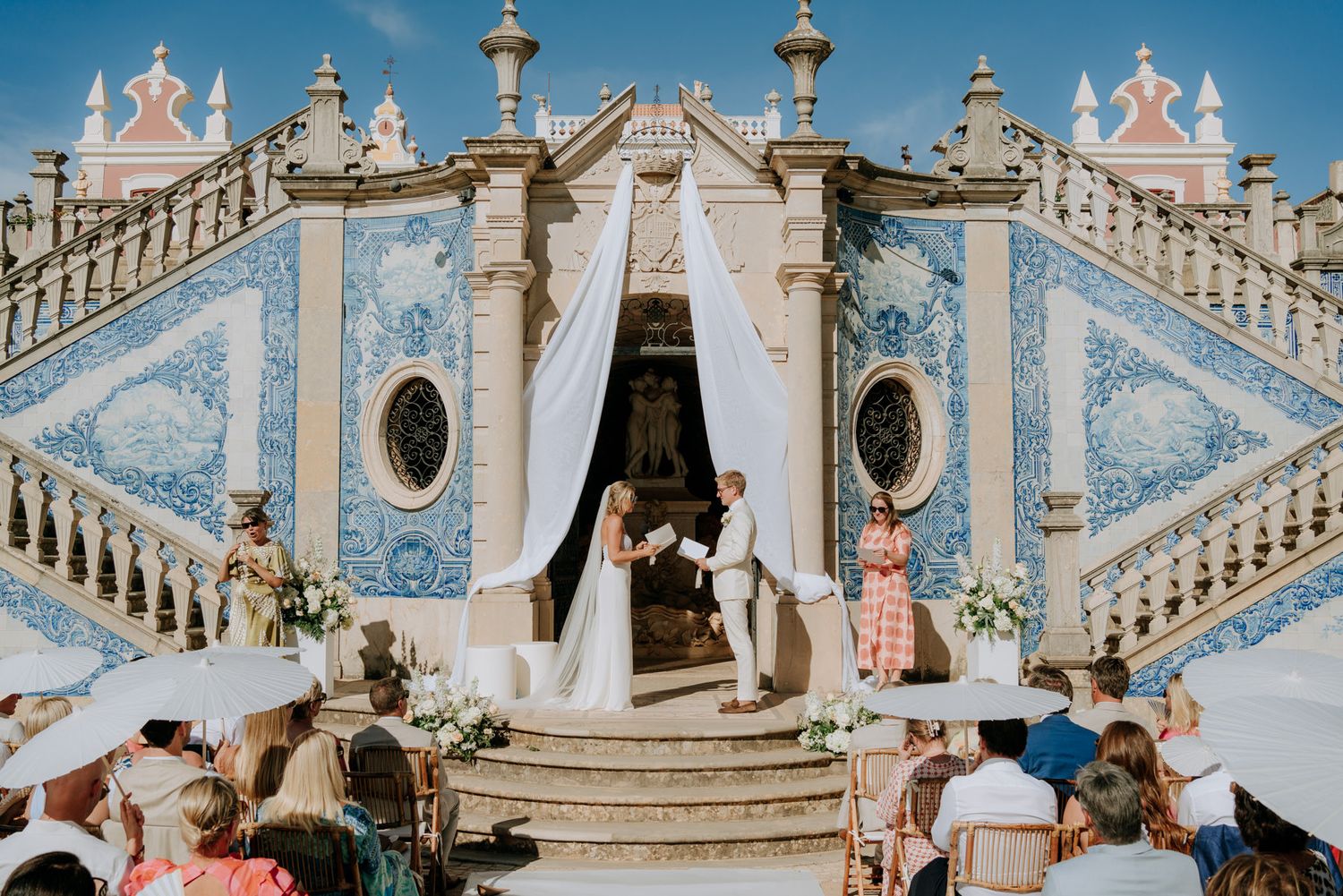 Couple exchanges vows at a stunning blue azulejo-tiled palace staircase during outdoor wedding ceremony.