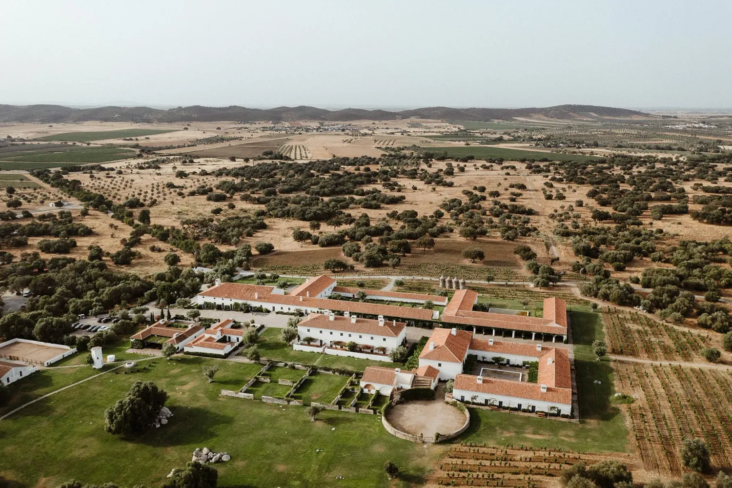 Aerial view of a sprawling Portuguese wedding estate with red-roofed buildings set amid vast open countryside.