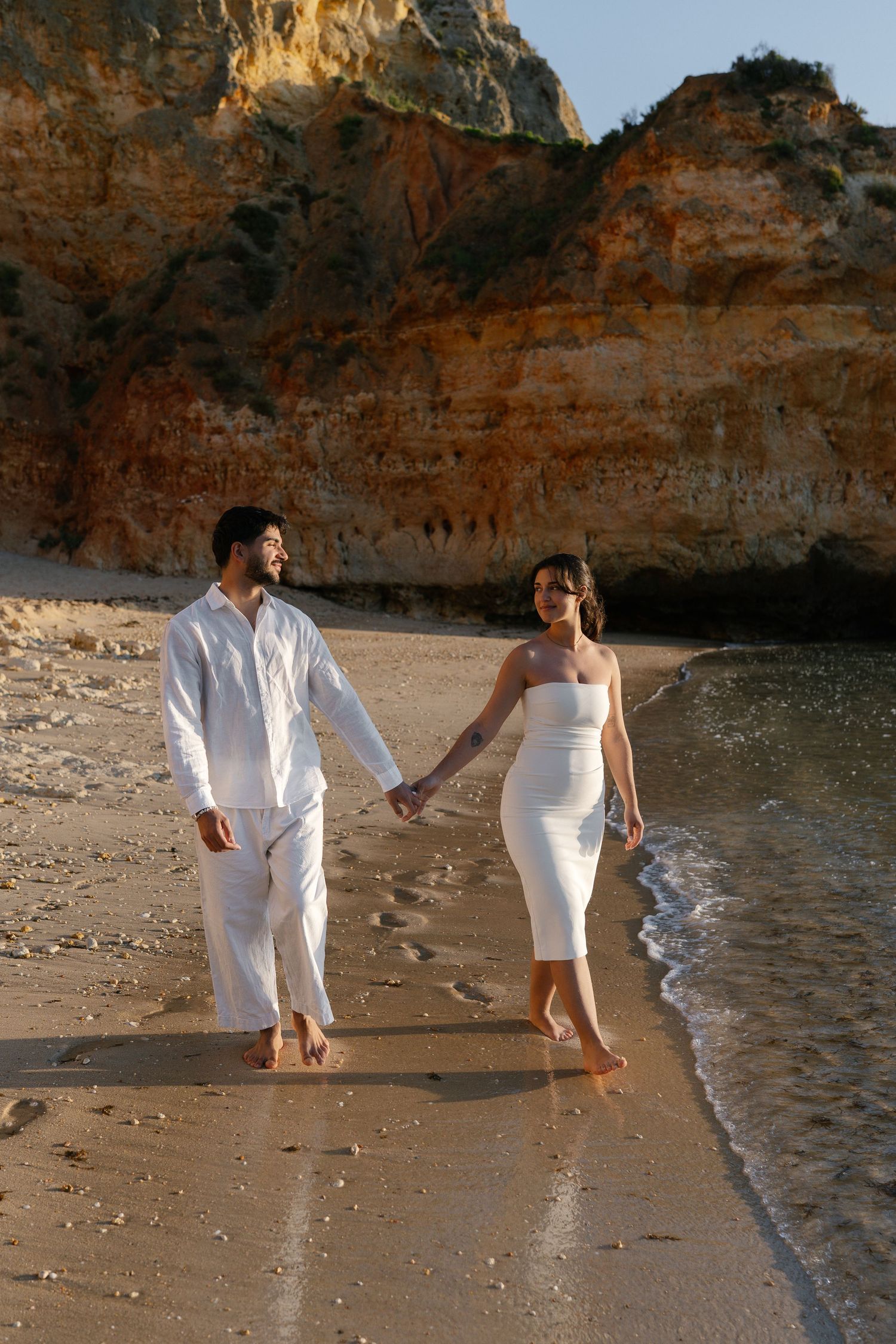 Couple enjoying a lovely walk on the sandy shores of Camilo Beach in the Algarve