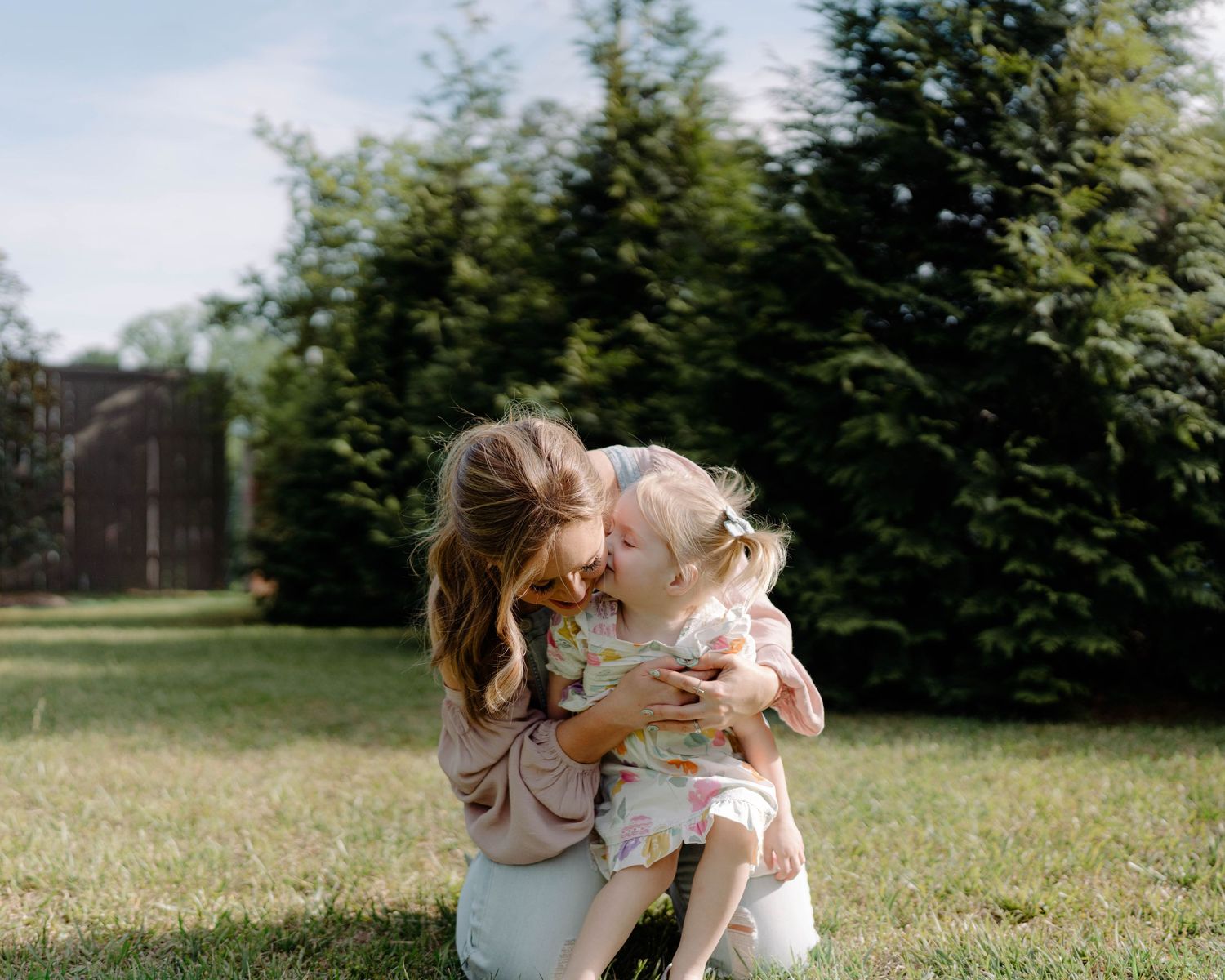 A heartwarming moment captured outdoors as a playful Golden Retriever gives affectionate kisses in a grassy backyard.