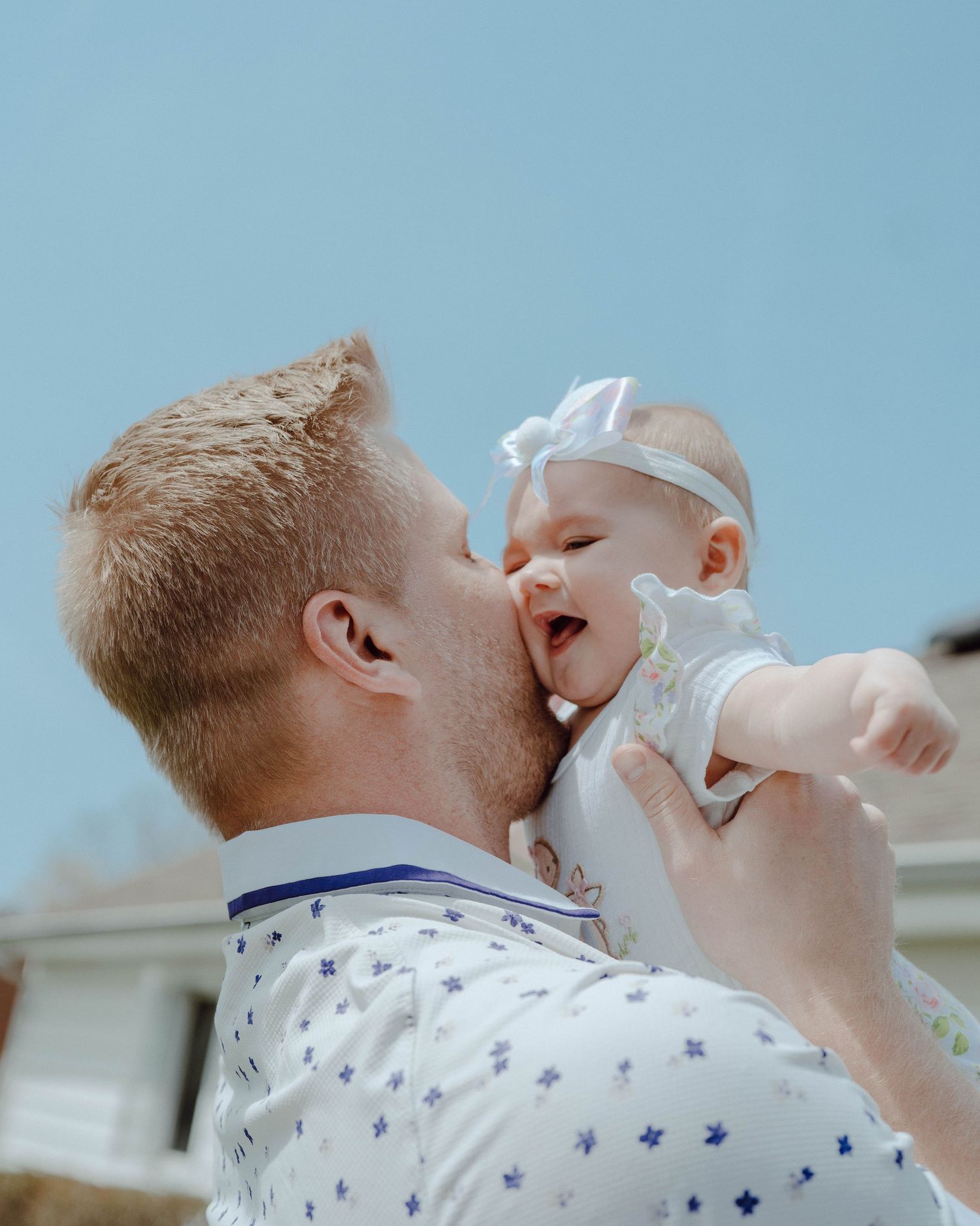 Happy interaction between parent and infant against blue sky background.