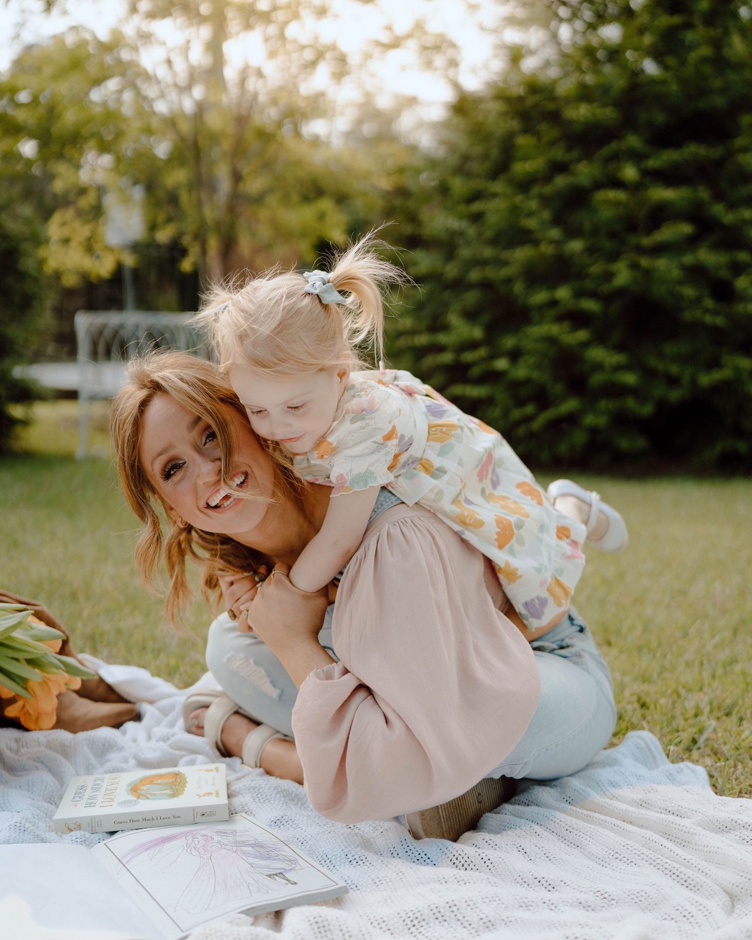 Heartwarming scene of people sharing a joyful moment together while having a picnic on a blanket in a sunny garden.