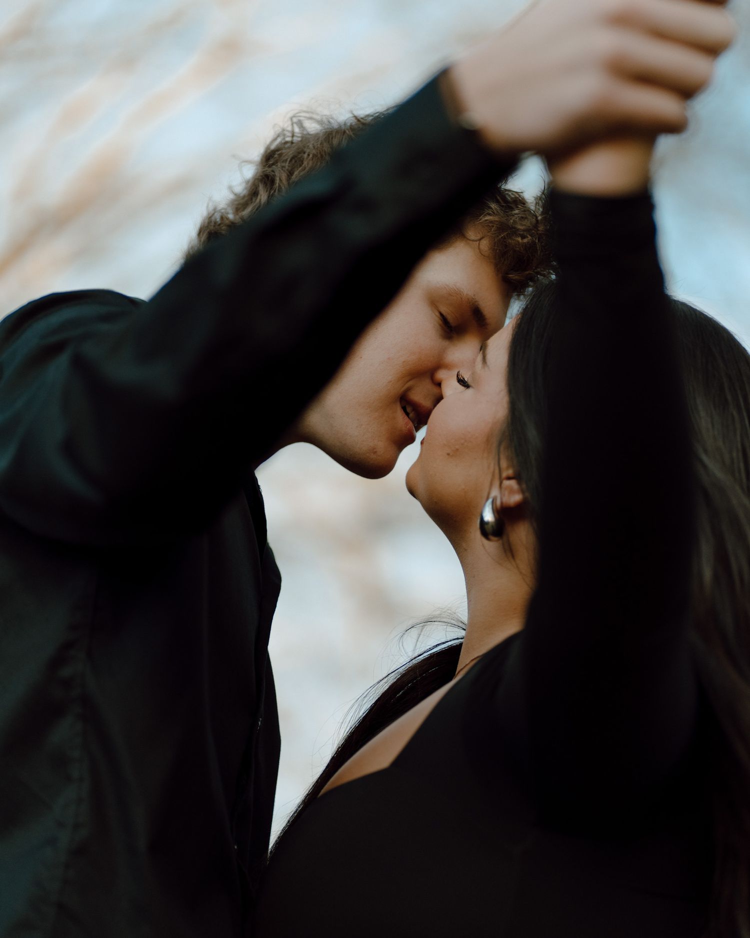 A romantic moment captured between a couple as they share an intimate kiss against a blurred background.