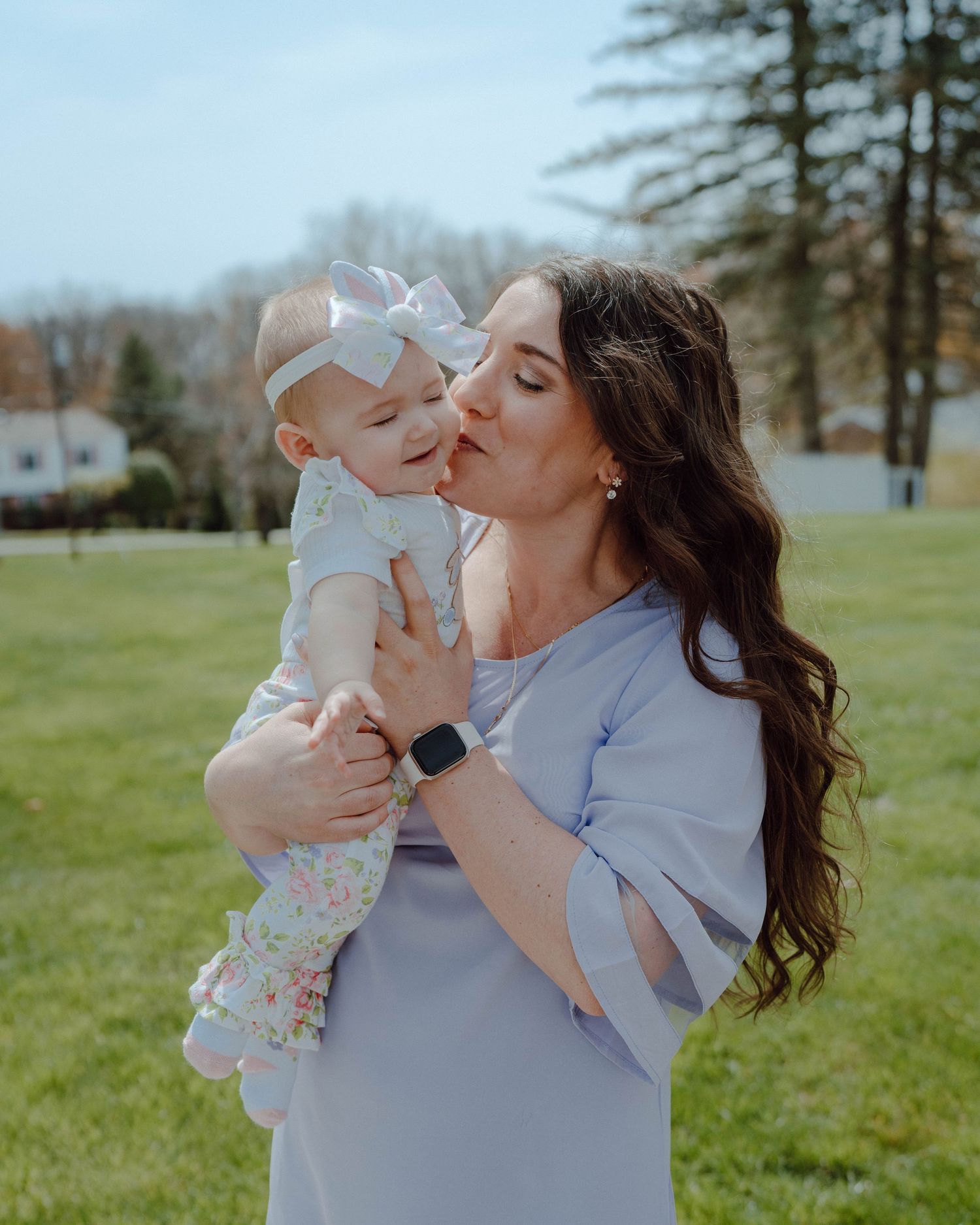 A tender moment shared between parent and baby on a sunny spring day in a grassy field.
