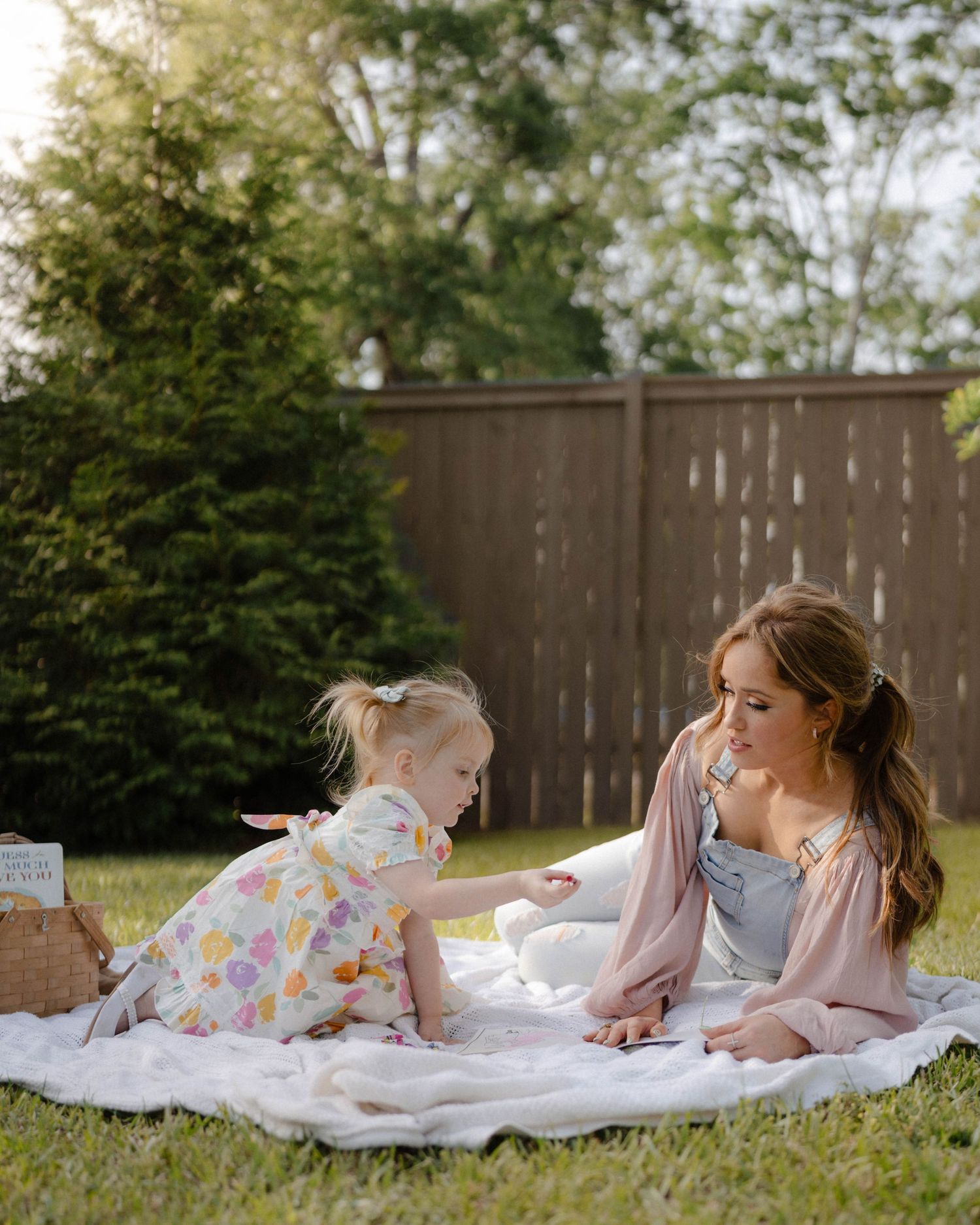 A relaxing afternoon picnic scene on a white blanket in a backyard garden with green surroundings.