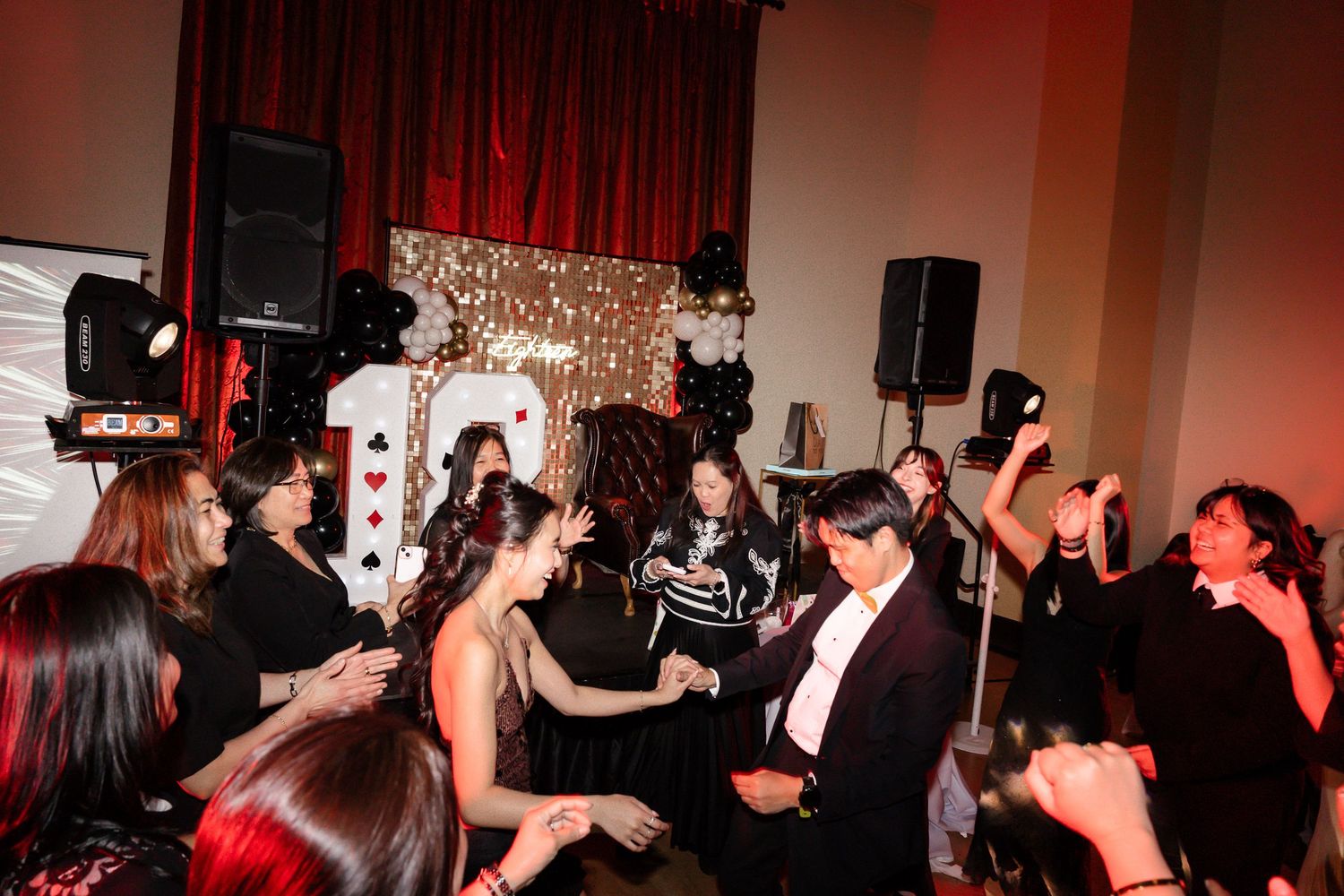 Guests dancing and celebrating at a festive party with balloon decorations and stage lighting.