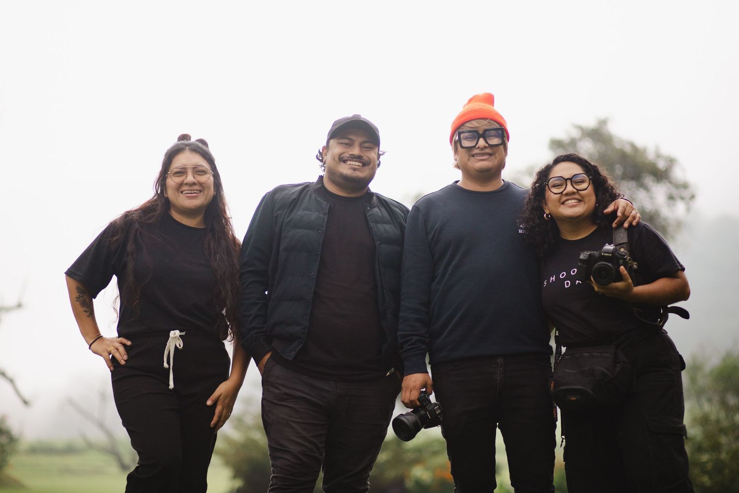 A group of people wearing black shirts pose together outdoors on a foggy day.