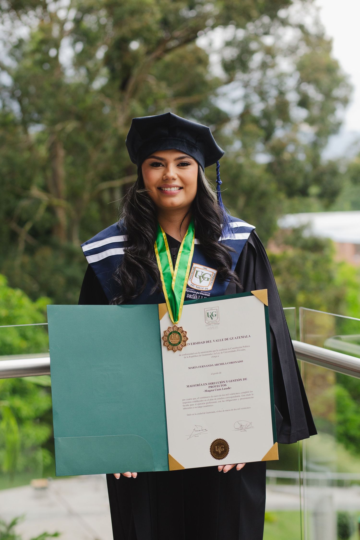 Graduate displays diploma folder in a series of celebratory graduation photos outdoors.