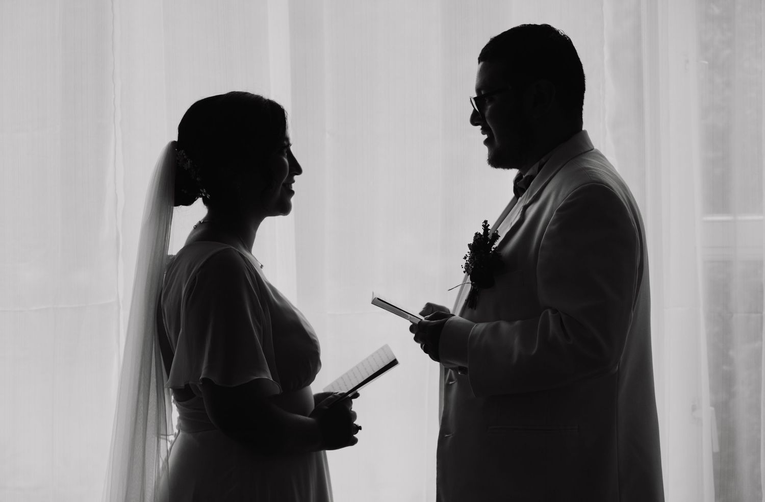 A row of backlit people looking at their smartphones, shown in silhouette against a bright window.