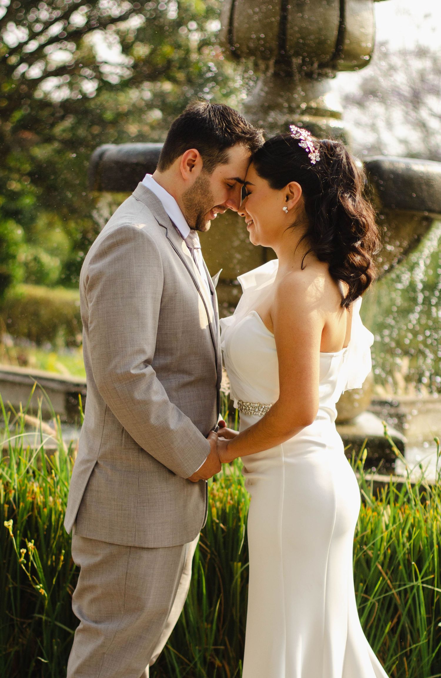 Romantic outdoor wedding moment in garden with fountain.