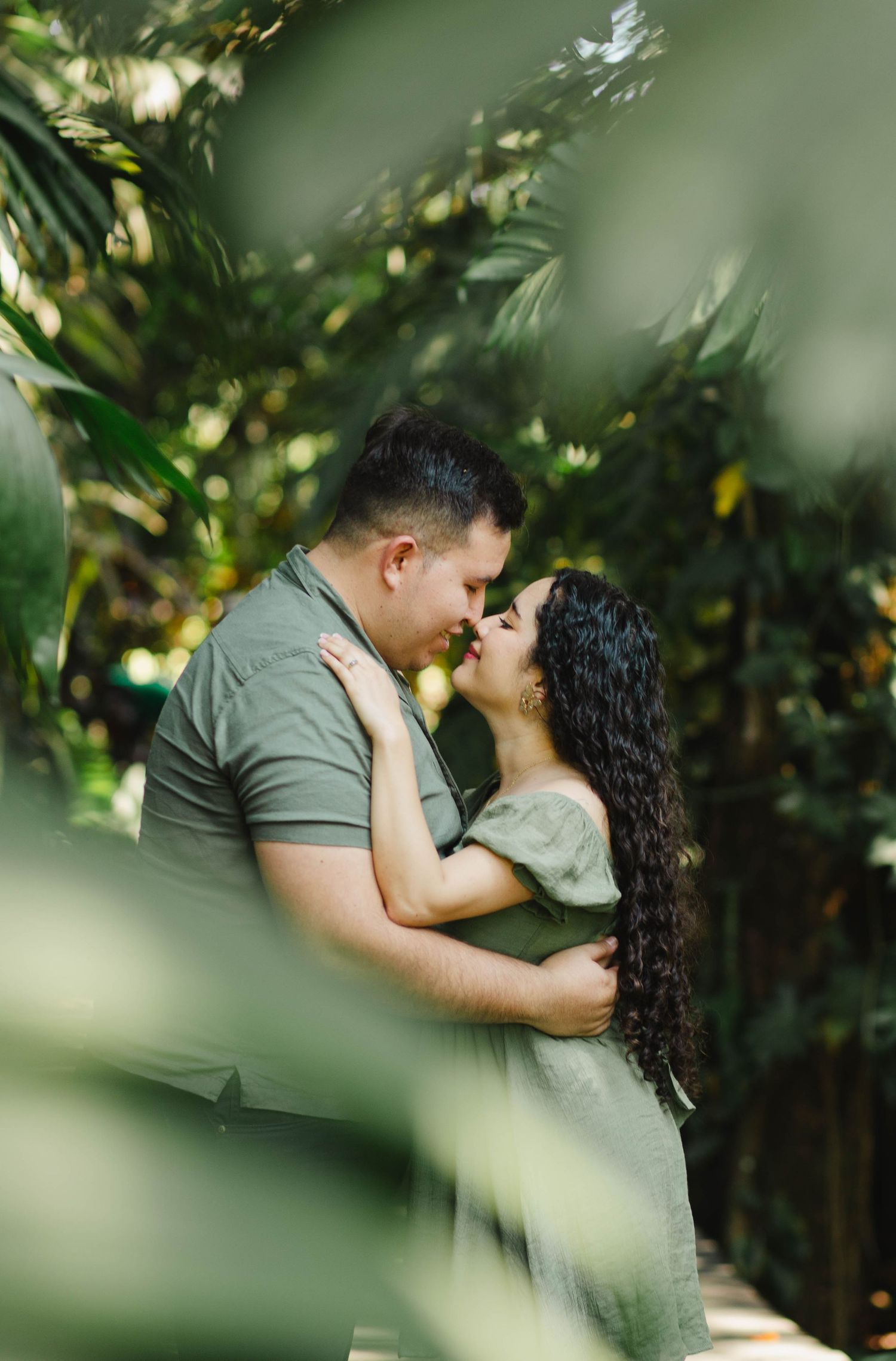 Romantic couple embraces in a lush garden setting with soft bokeh lighting effects.