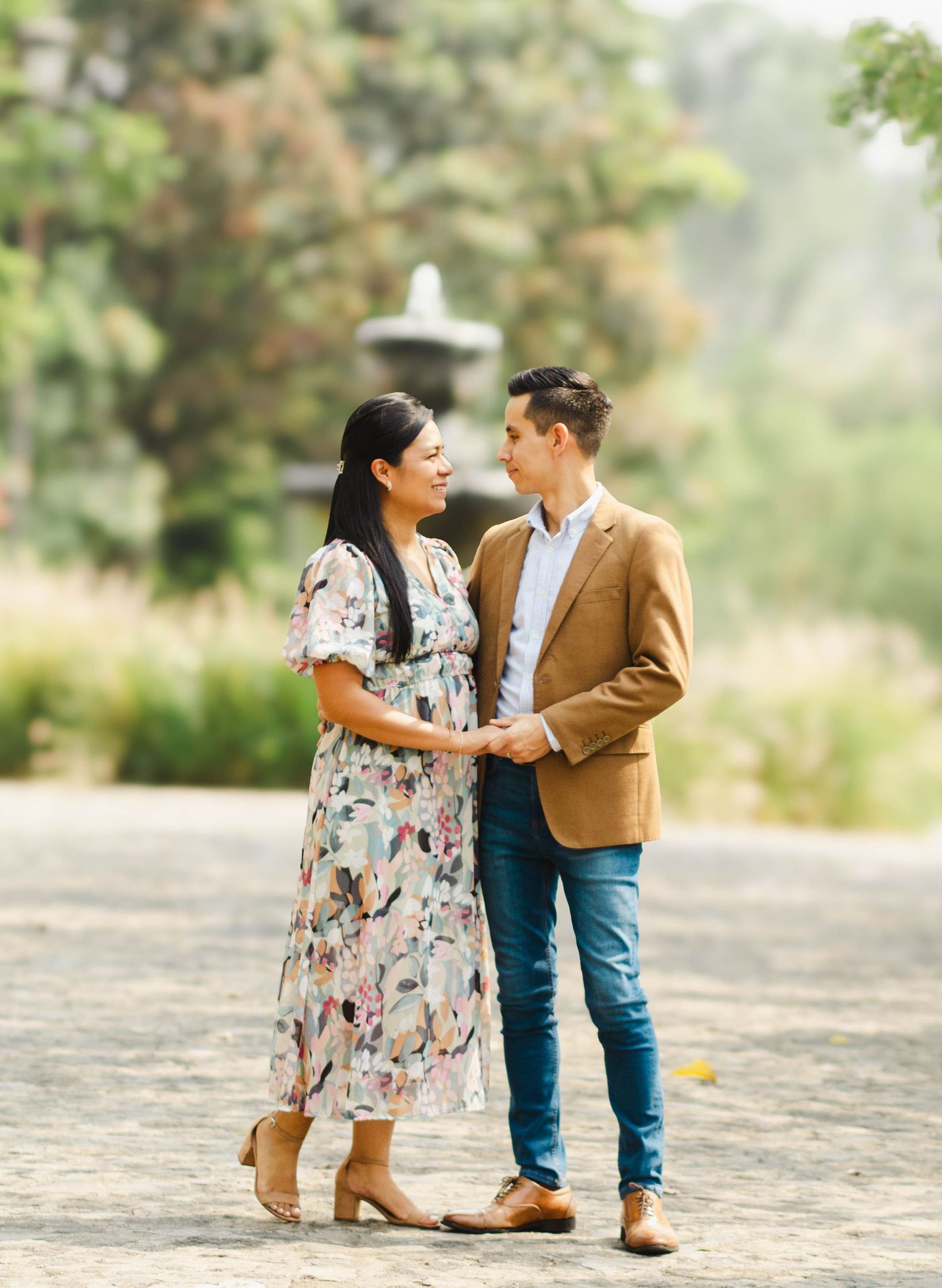 Couple in formal attire sharing intimate moment on garden path surrounded by greenery.