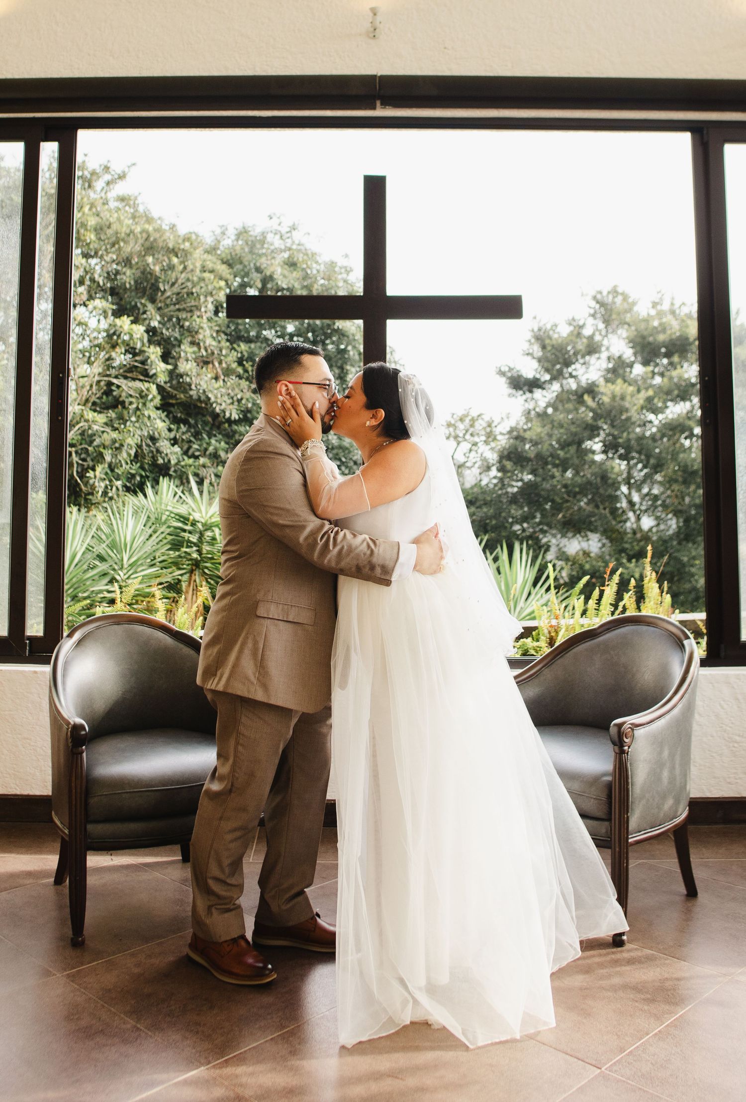 A couple shares a romantic dance moment on a covered patio with lush greenery visible in the background.
