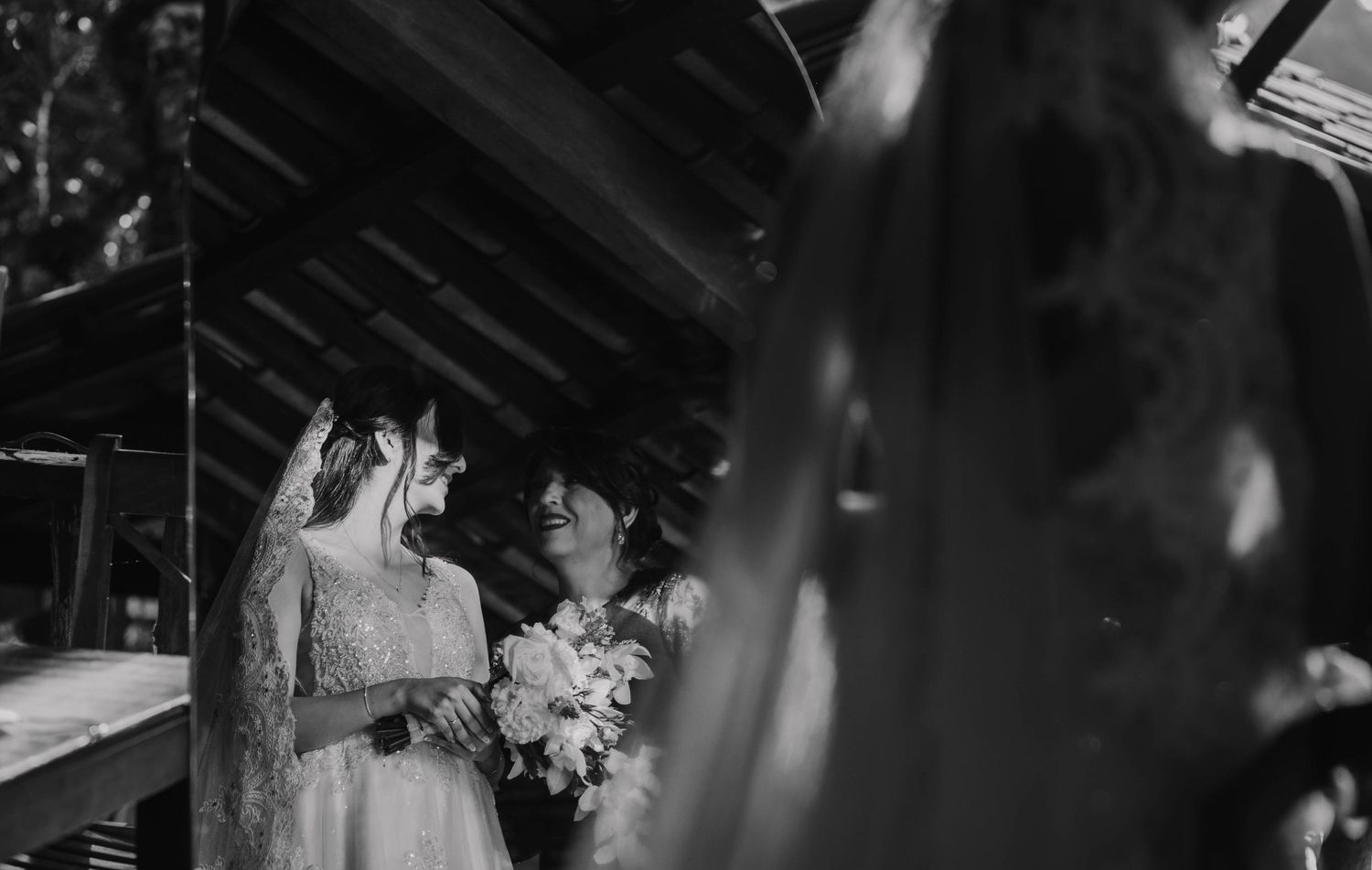Black and white intimate wedding ceremony moment under rustic wooden beams.