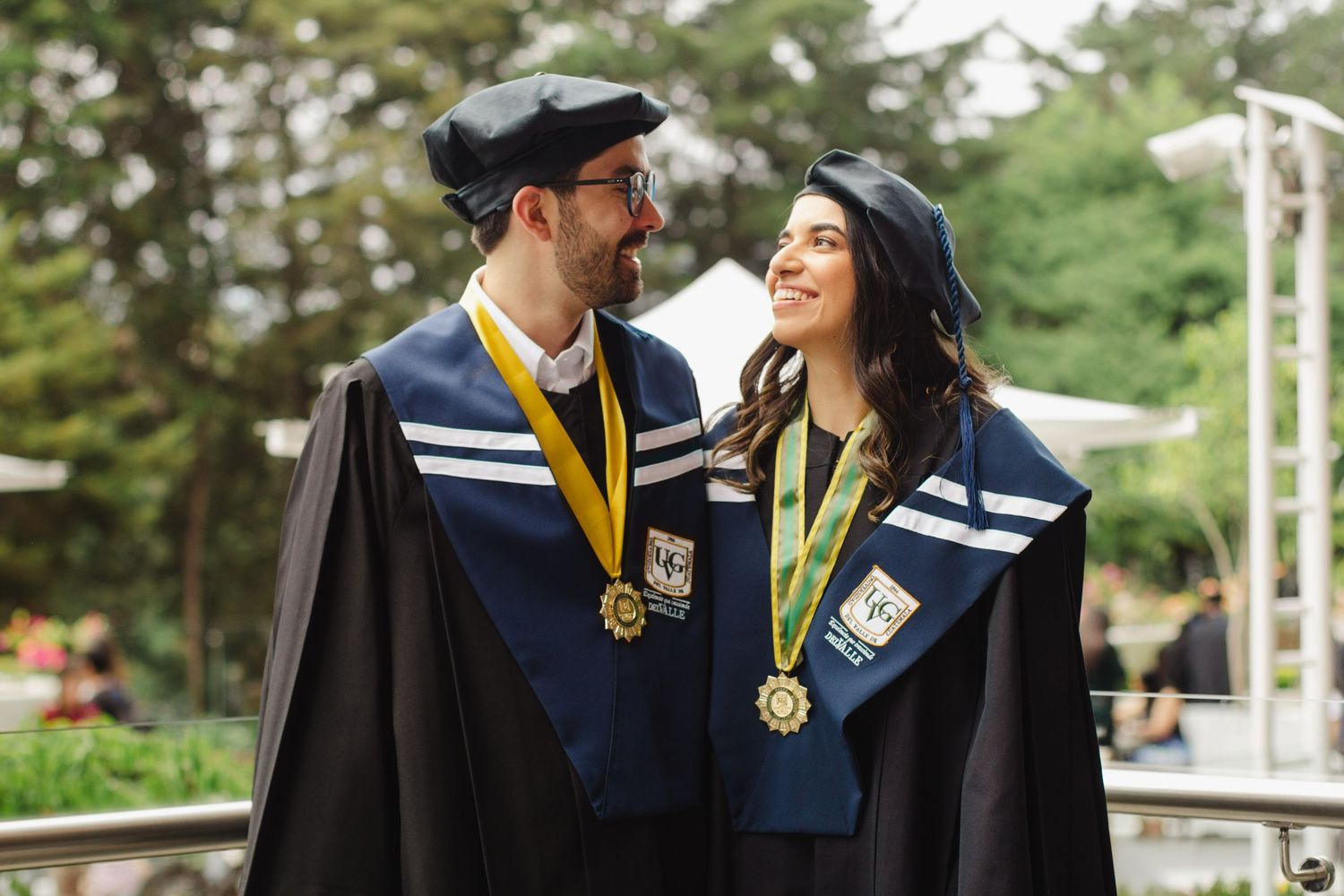 Two graduates in matching caps and gowns share a joyful moment at their graduation ceremony.