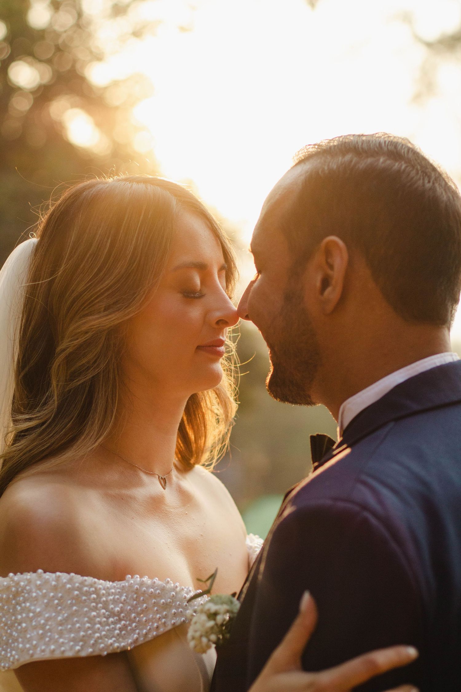 Romantic couple sharing an intimate moment in golden sunlight at their wedding.