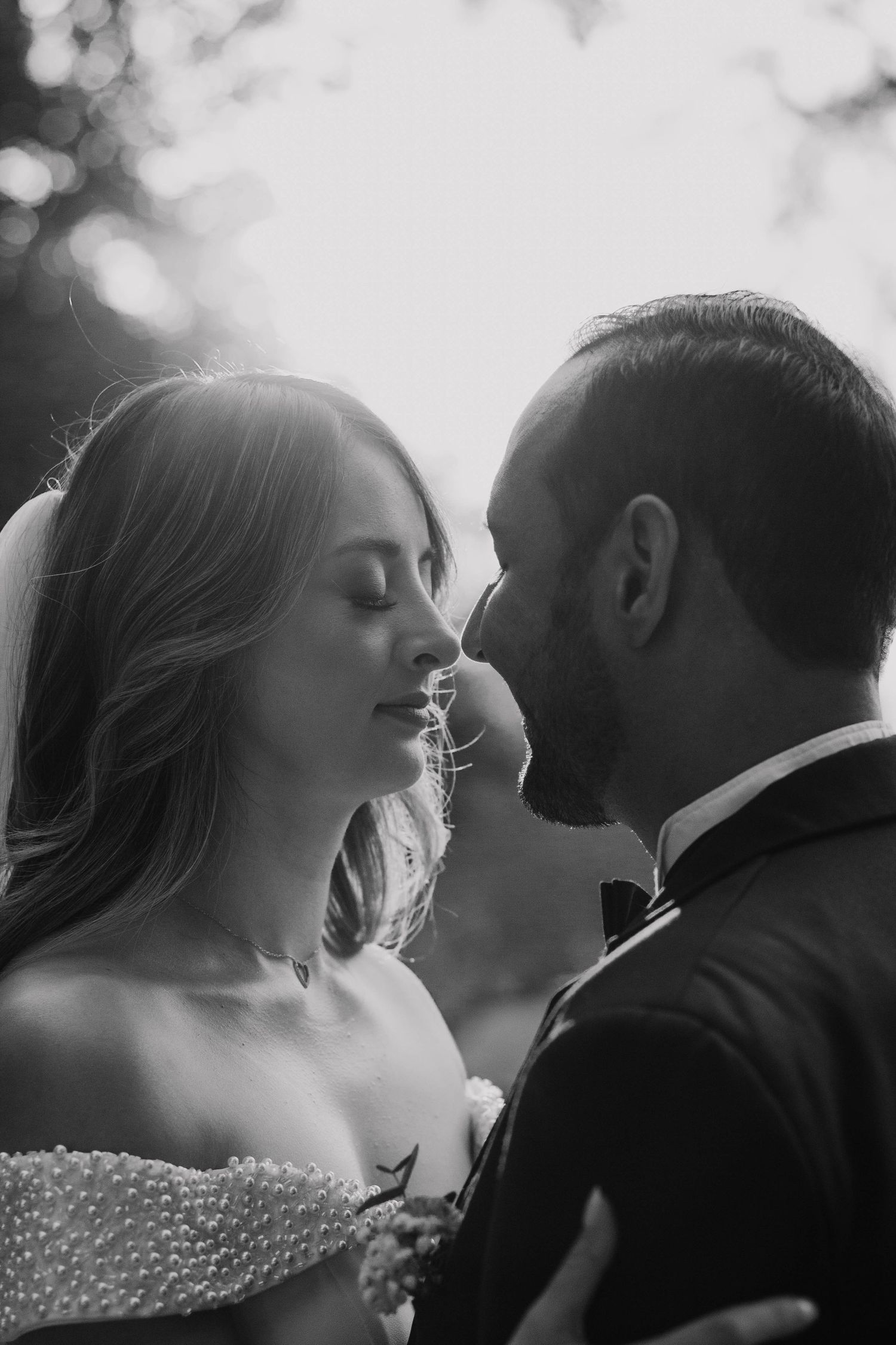 Intimate black and white portrait of a couple in wedding attire sharing a tender moment.