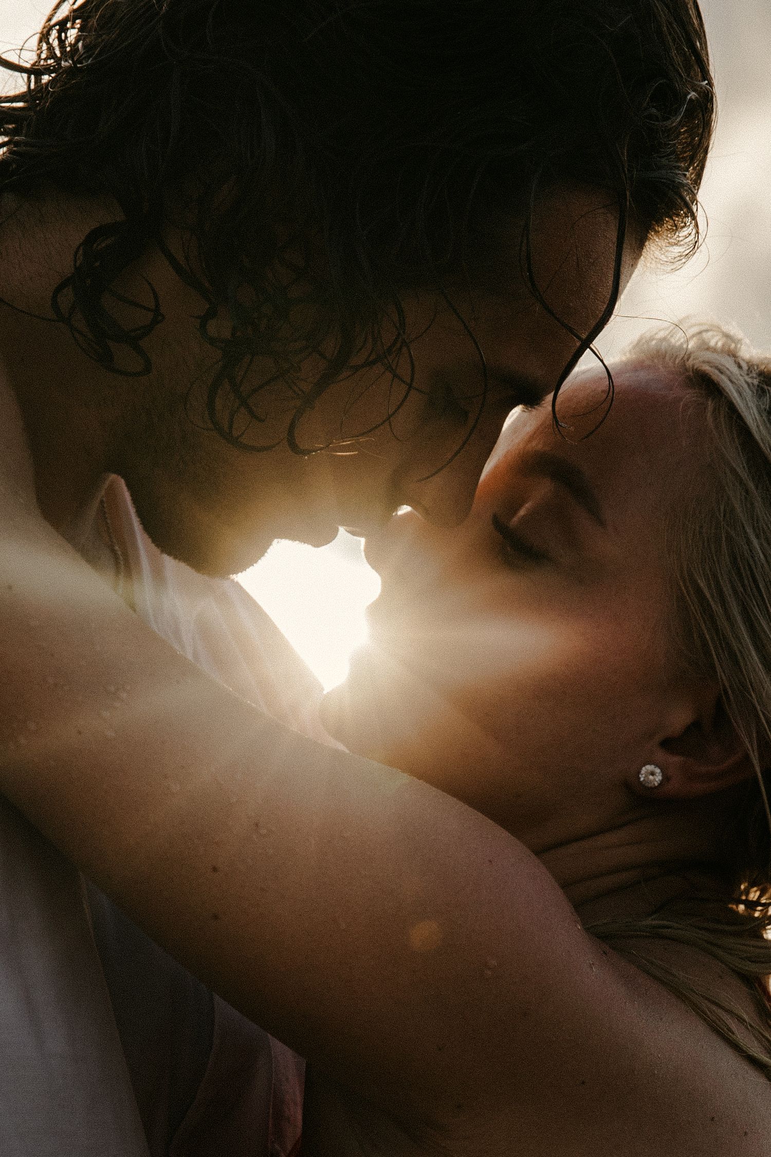 A romantic silhouette of a couple sharing an intimate moment with sunlight glowing between them.