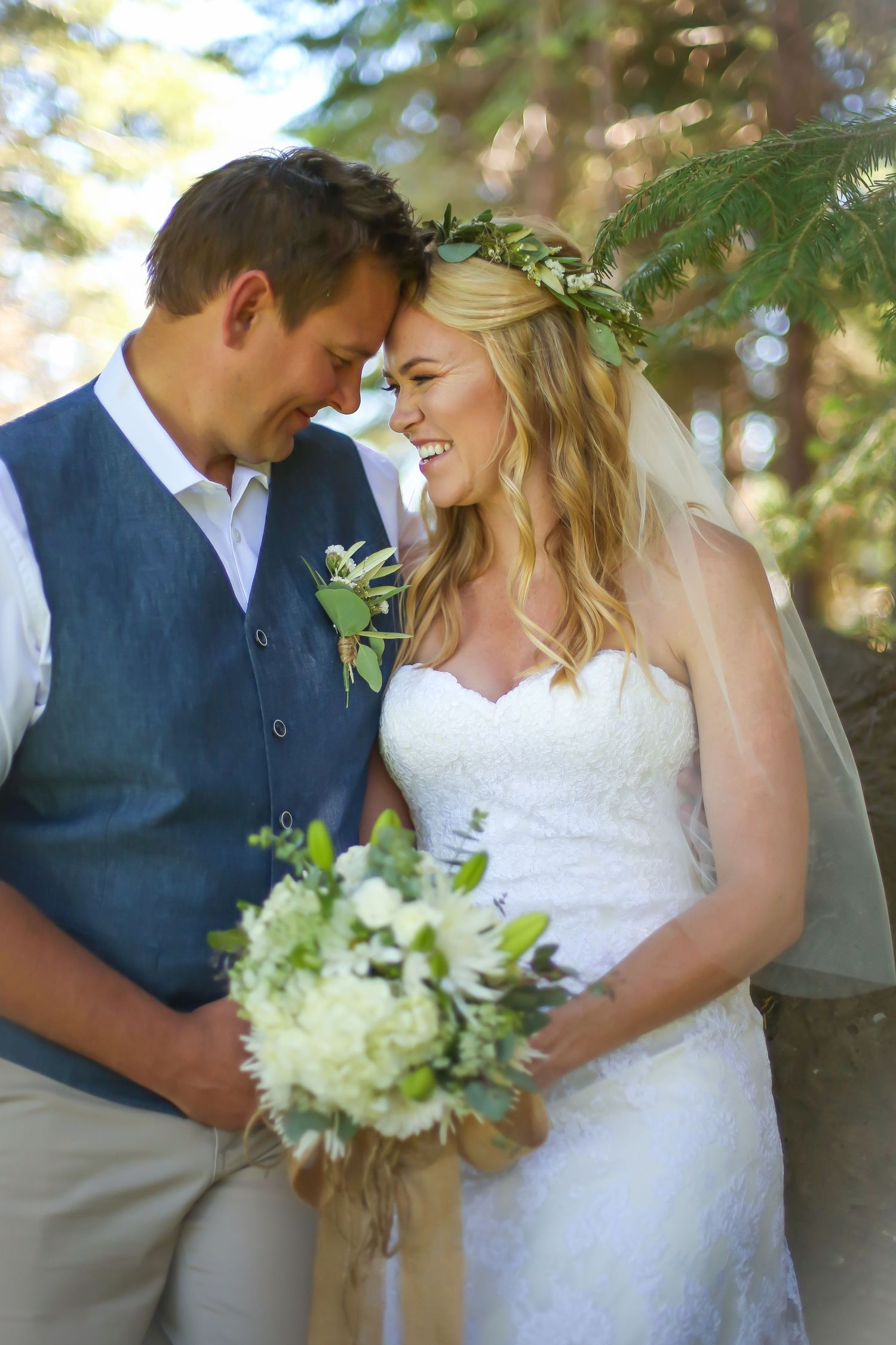 A couple shares an intimate moment in wedding attire against a natural backdrop.