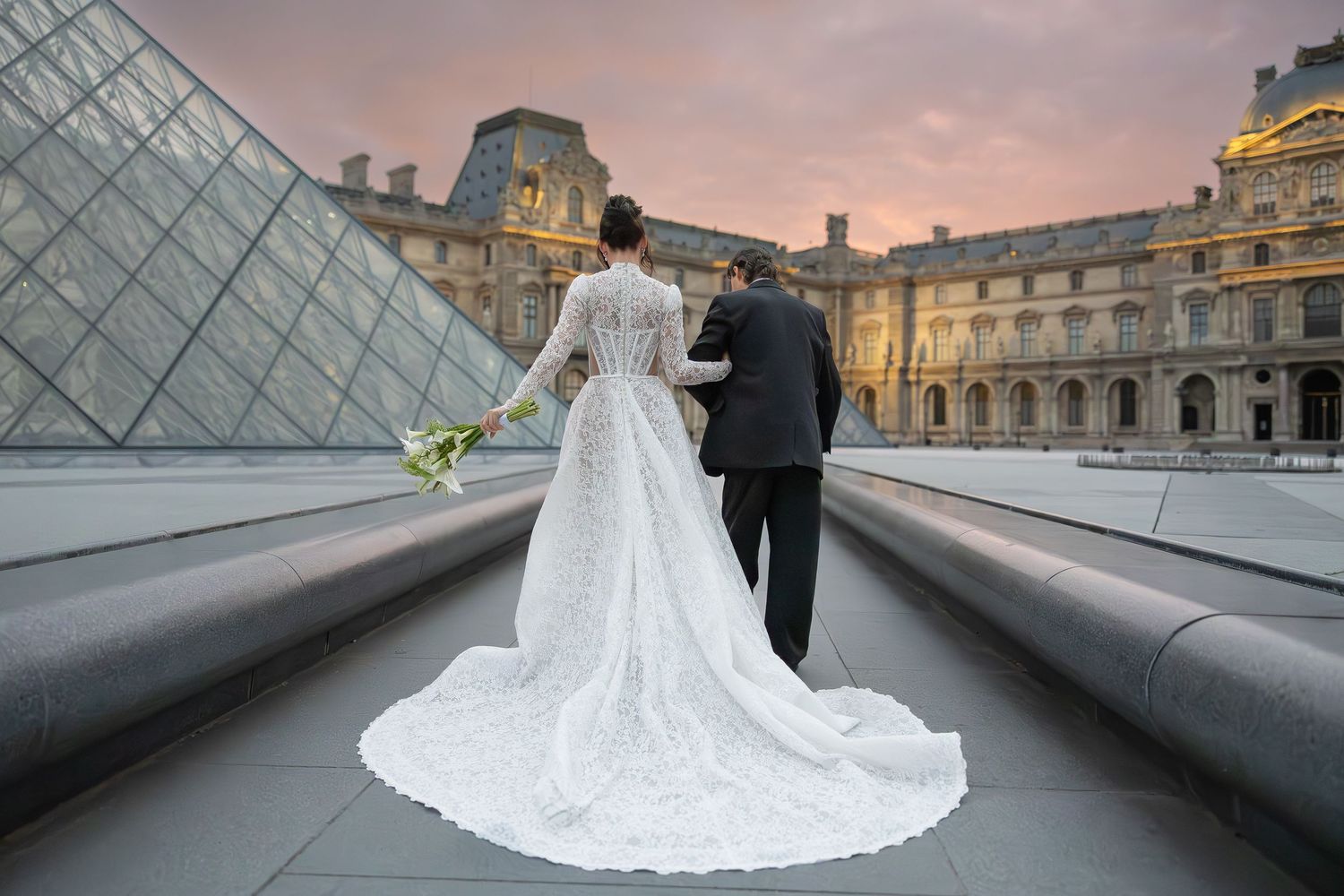 Wedding couple poses in front of the Louvre pyramid during sunset in Paris.