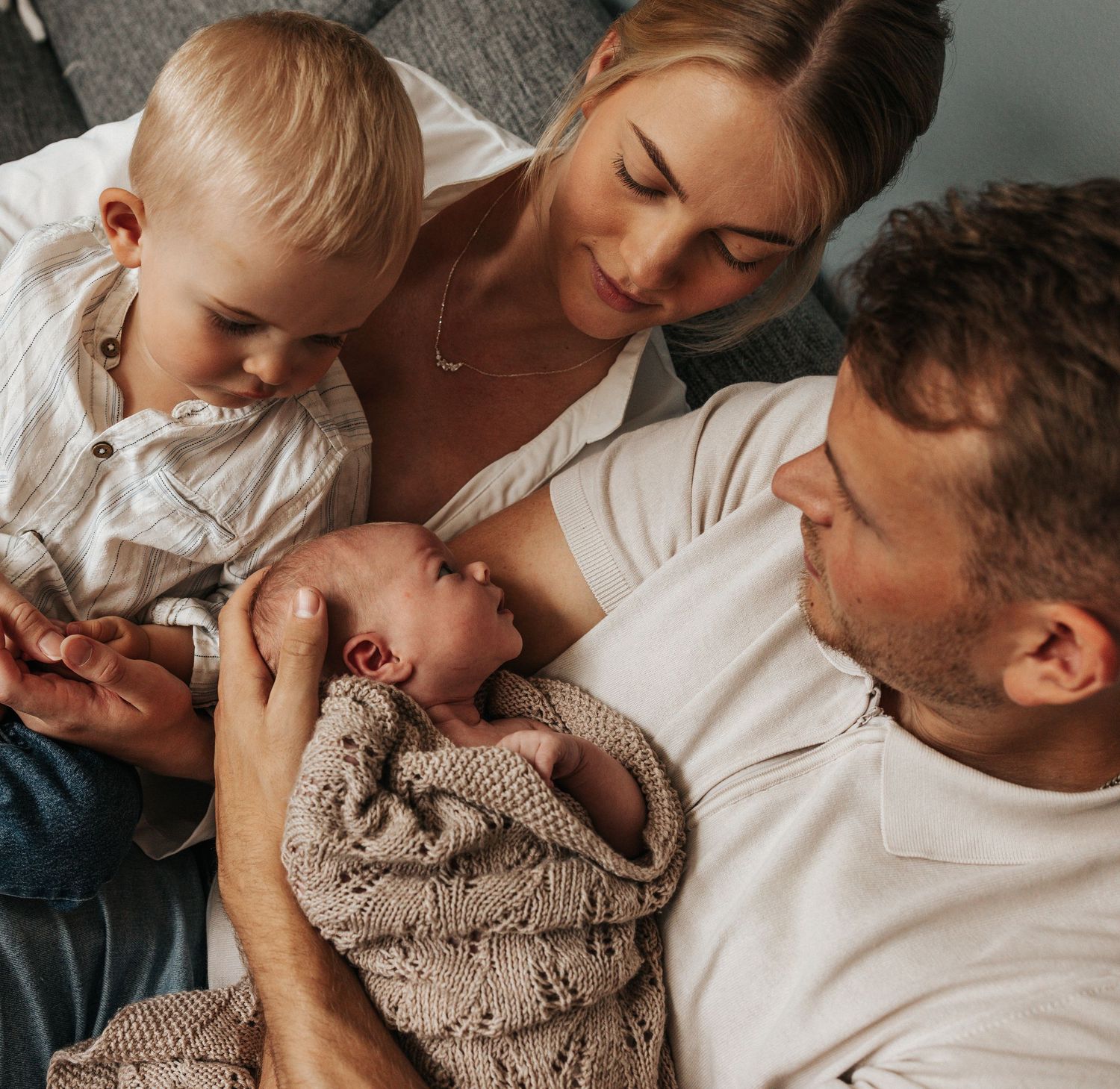 Family with newborn baby and toddler sharing tender moment together.