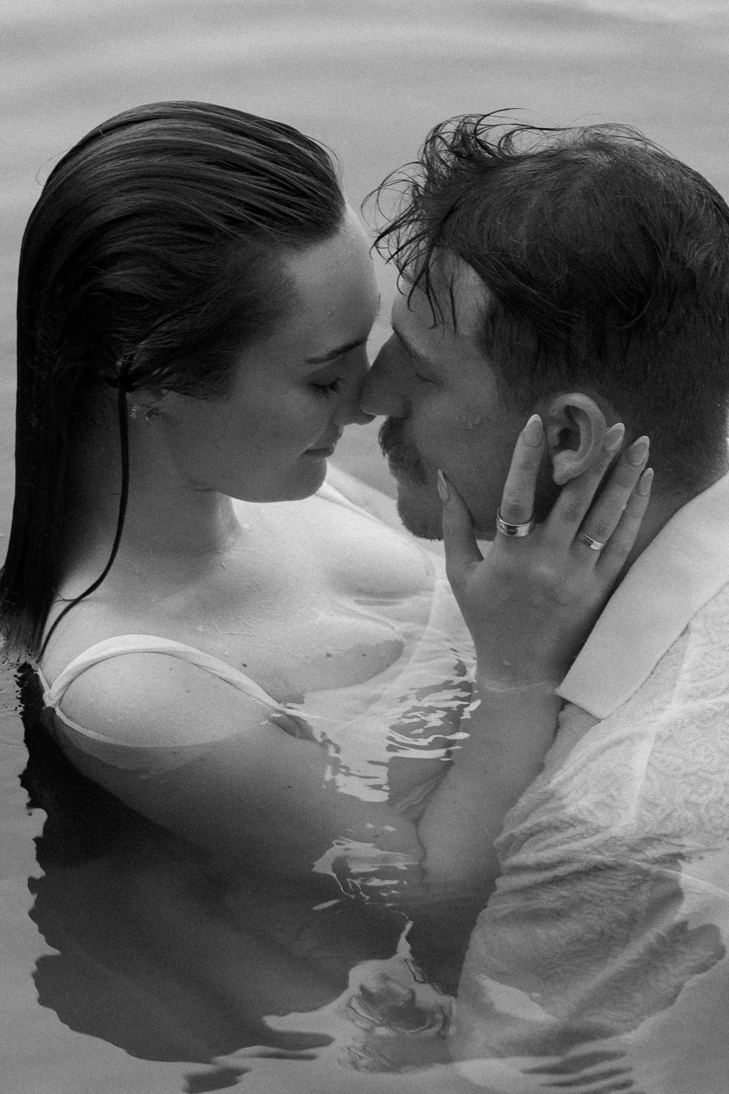 Black and white photo of a romantic couple sharing an intimate moment while standing together in water.