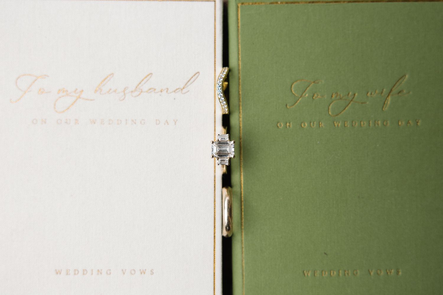Cream and green wedding vow books reading To my husband and To my wife with diamond ring resting between them.