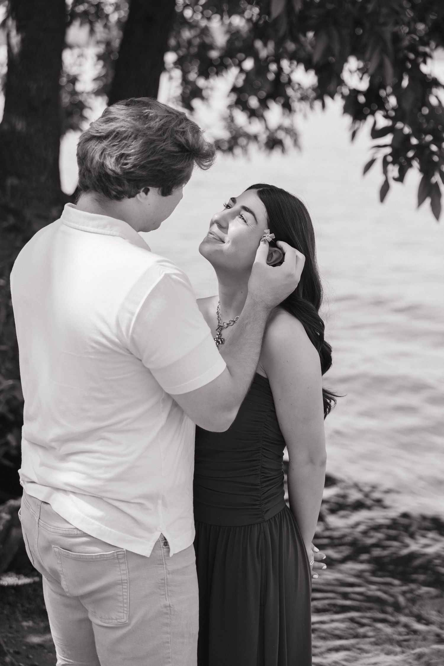 Black and white image of a couple sharing an intimate moment by a lake.