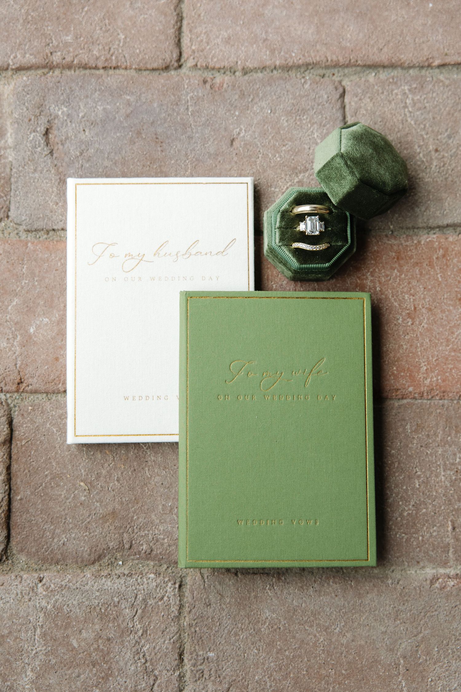 Green vow books reading To my husband and To my wife beside green velvet ring box with diamond wedding rings.