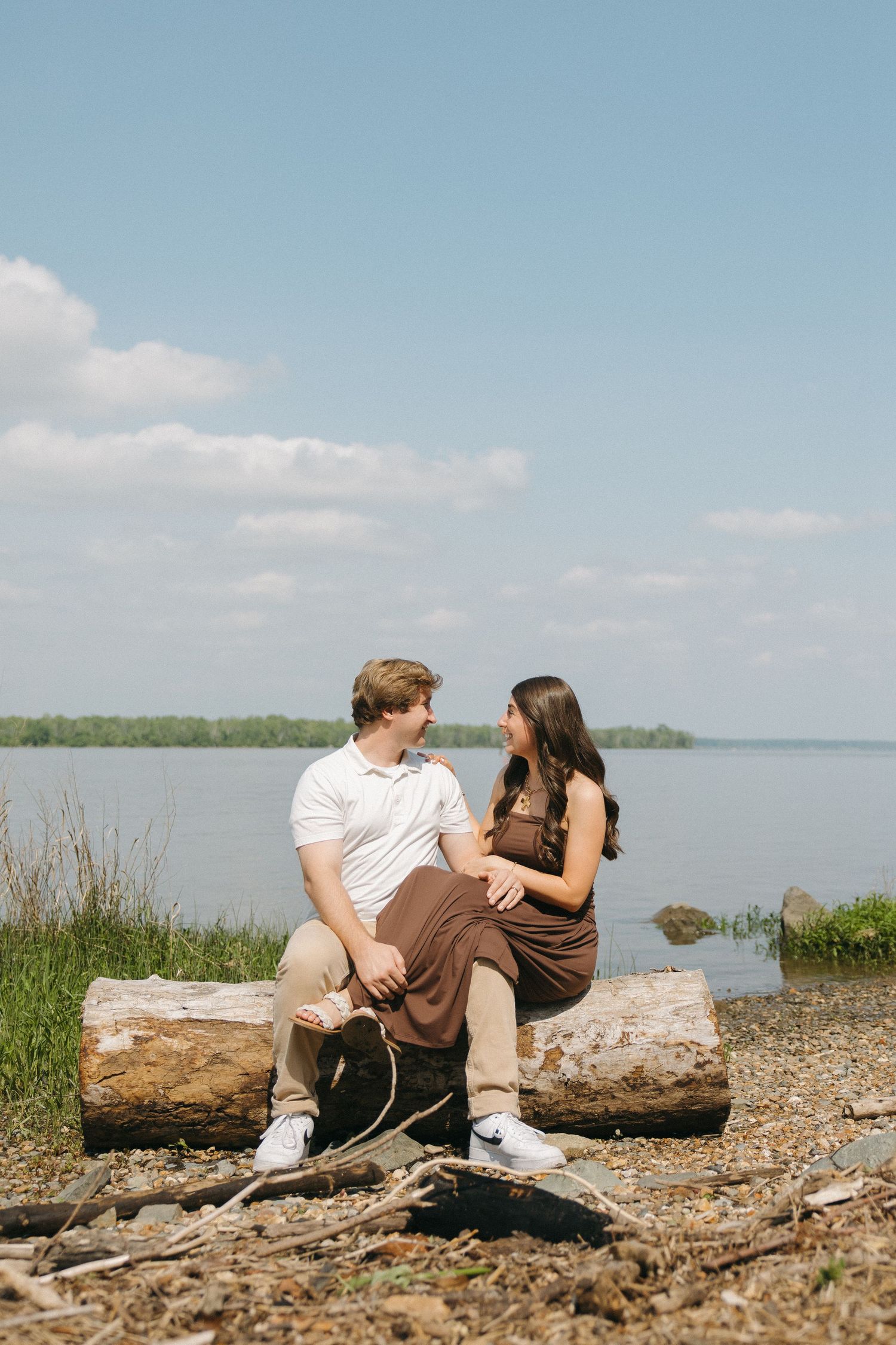 Couple sitting on a log by the lake enjoying a sunny day together.