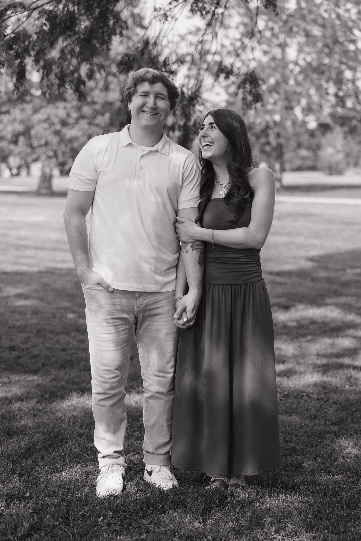 Black and white portrait of a happy couple holding hands and smiling in a park.