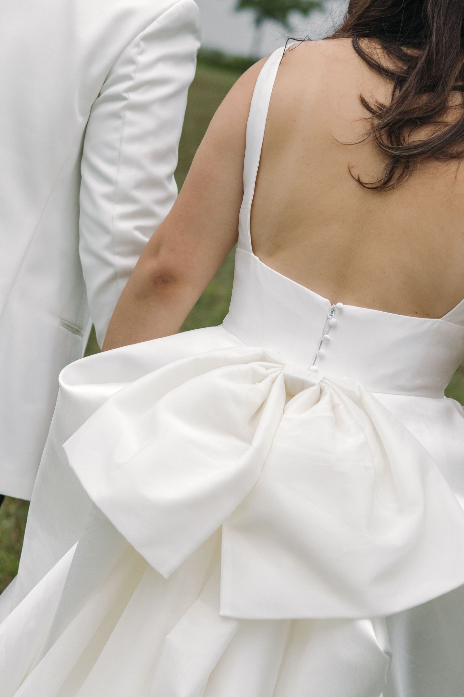 Close-up back view of bride's white wedding gown featuring large oversized bow detail.